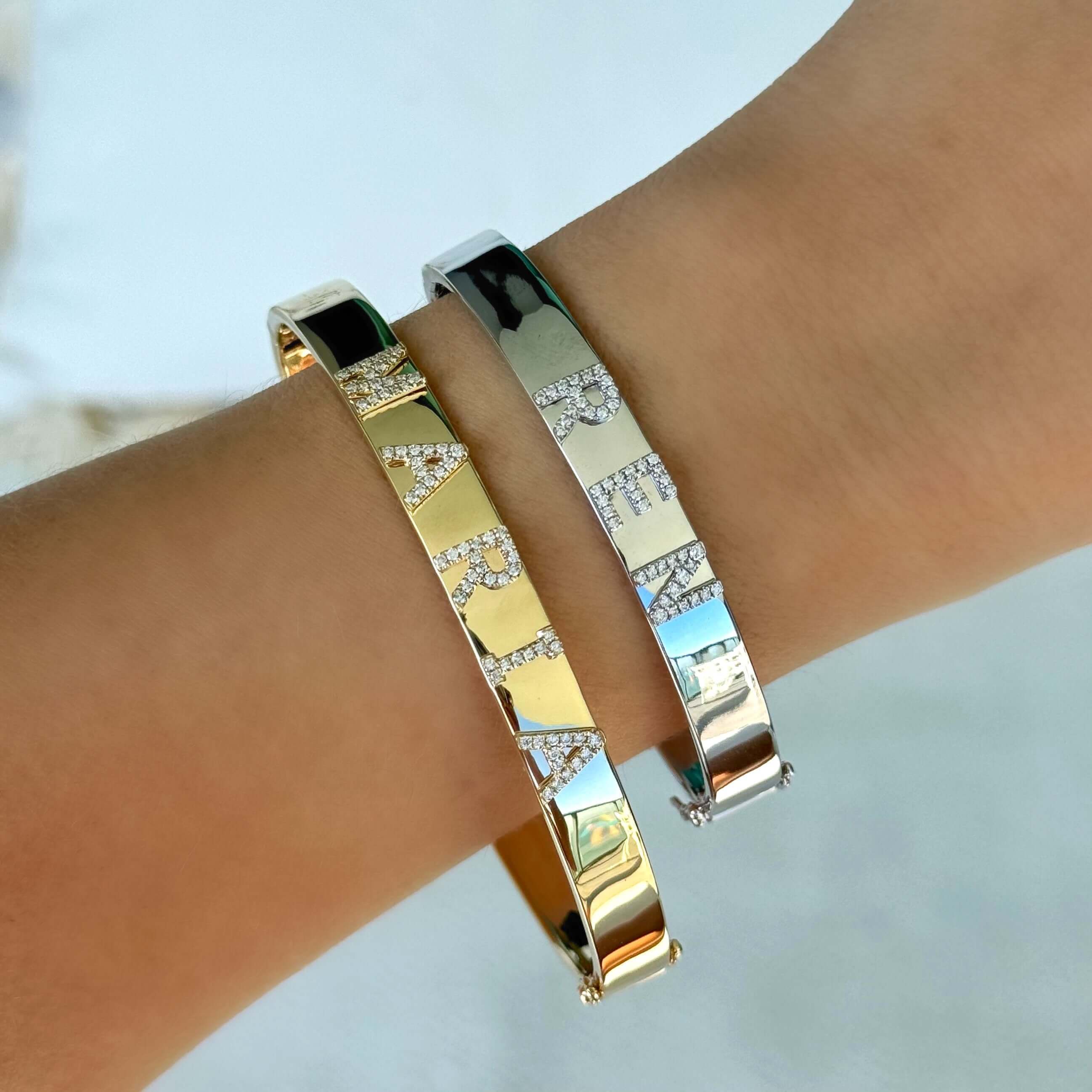 Elegant gold and silver bracelets by our jewelry brand, featuring geometric designs and accent diamonds, showcased on a wrist.