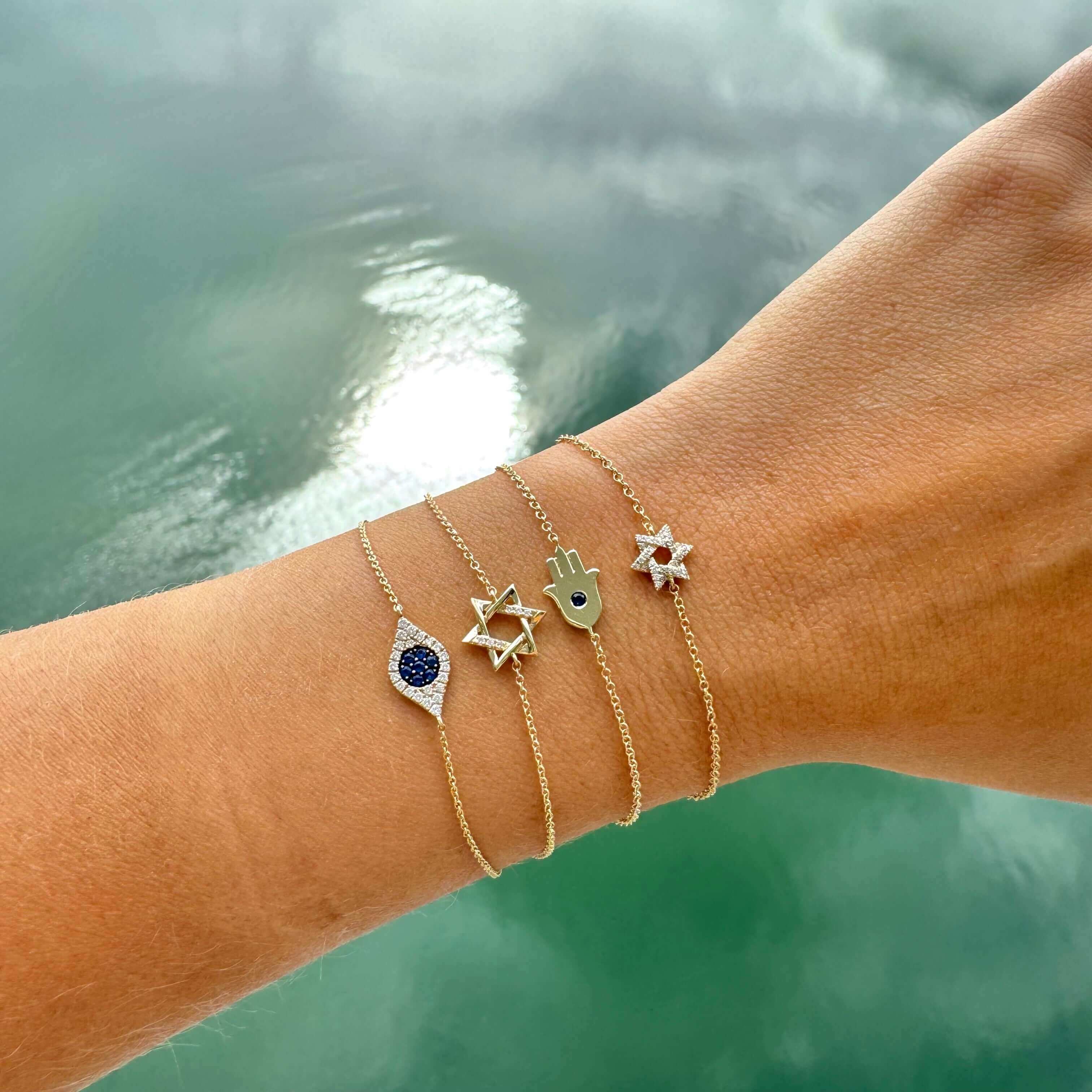Gold jewelry bracelets with trendy charms and a view of water in the background from our exclusive jewelry collection