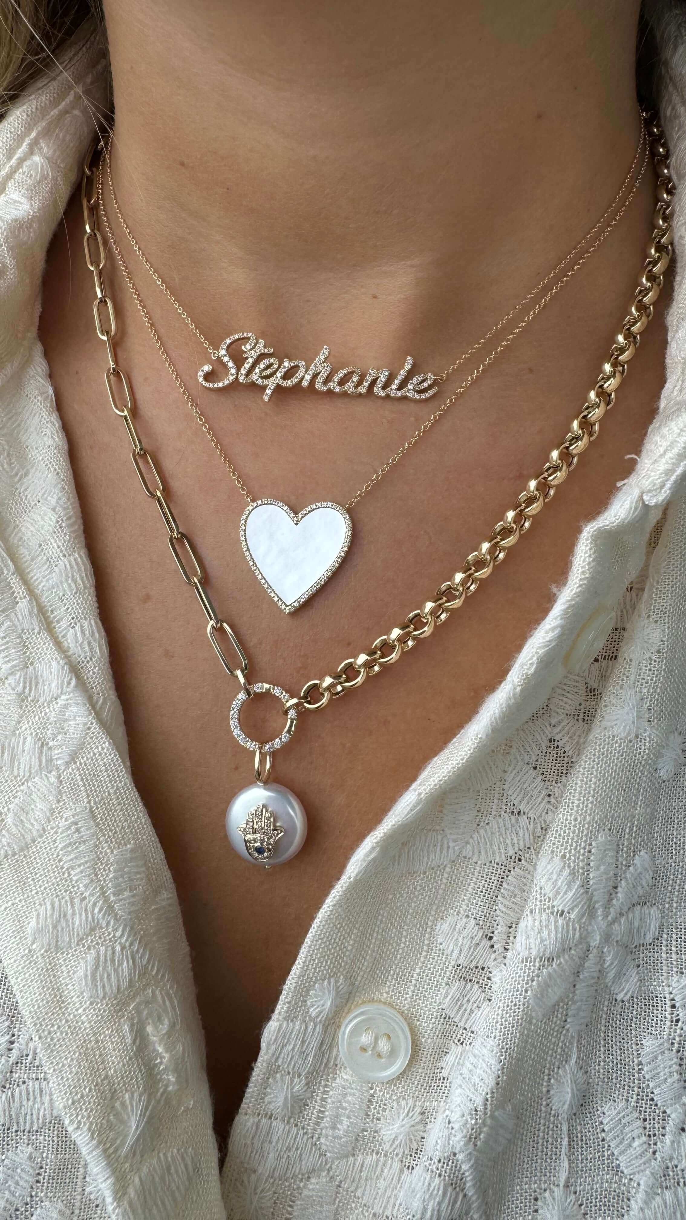 Layered necklaces with heart pendant and 'Stephanie' nameplate on woman wearing lace blouse