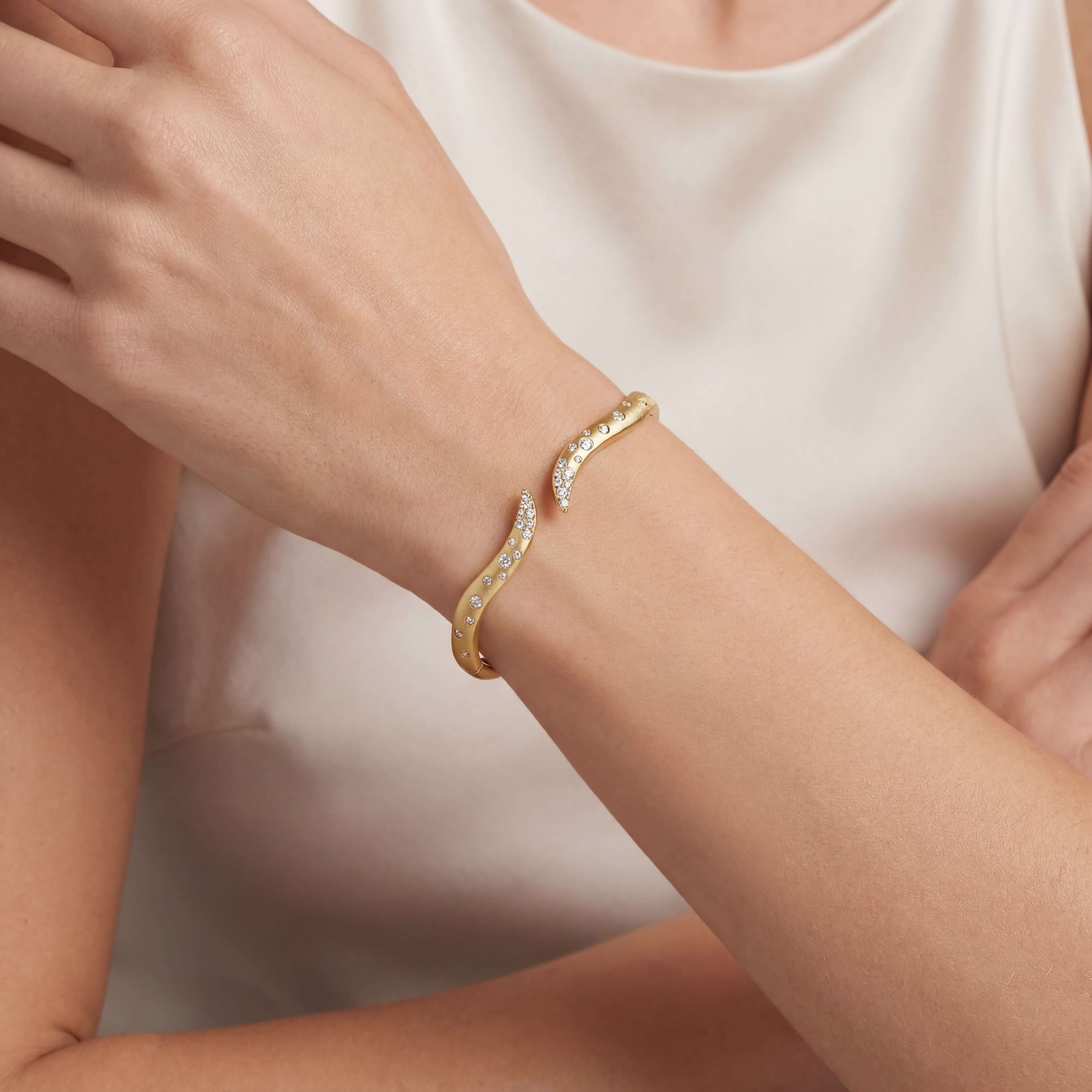 Wavy Diamond Confetti Cuff Bangle elegantly worn on a model's wrist showcasing its shimmering diamonds and gold design.