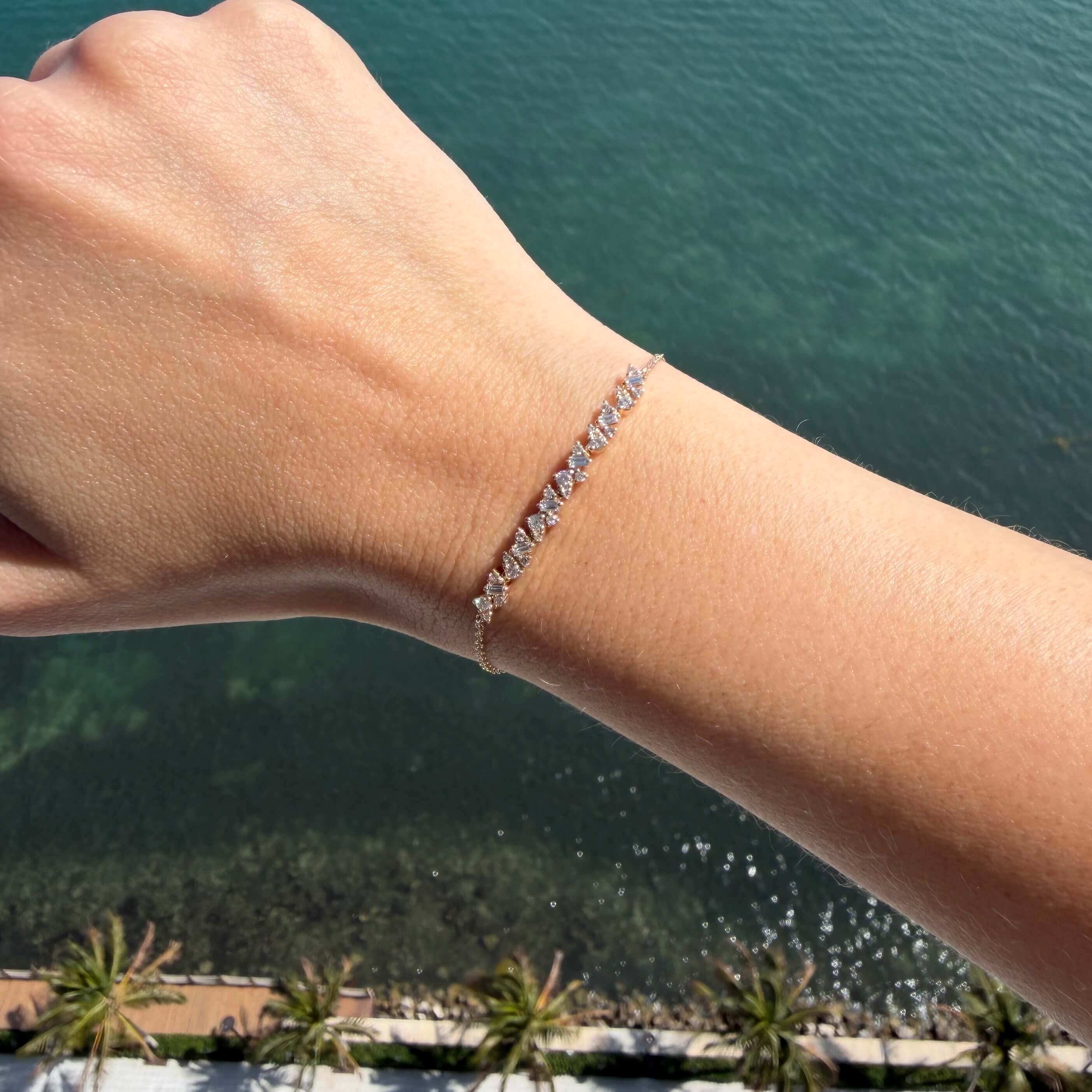 Baguette & Round Diamond Cluster Bracelet showcased on a hand above a waterfront view.