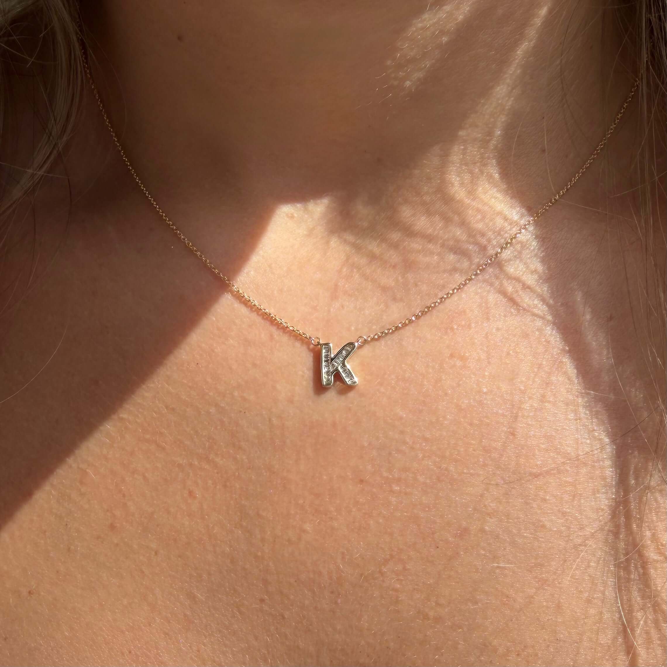 Baguette Diamond Letter Necklace featuring a diamond 'K' pendant worn on a delicate chain.