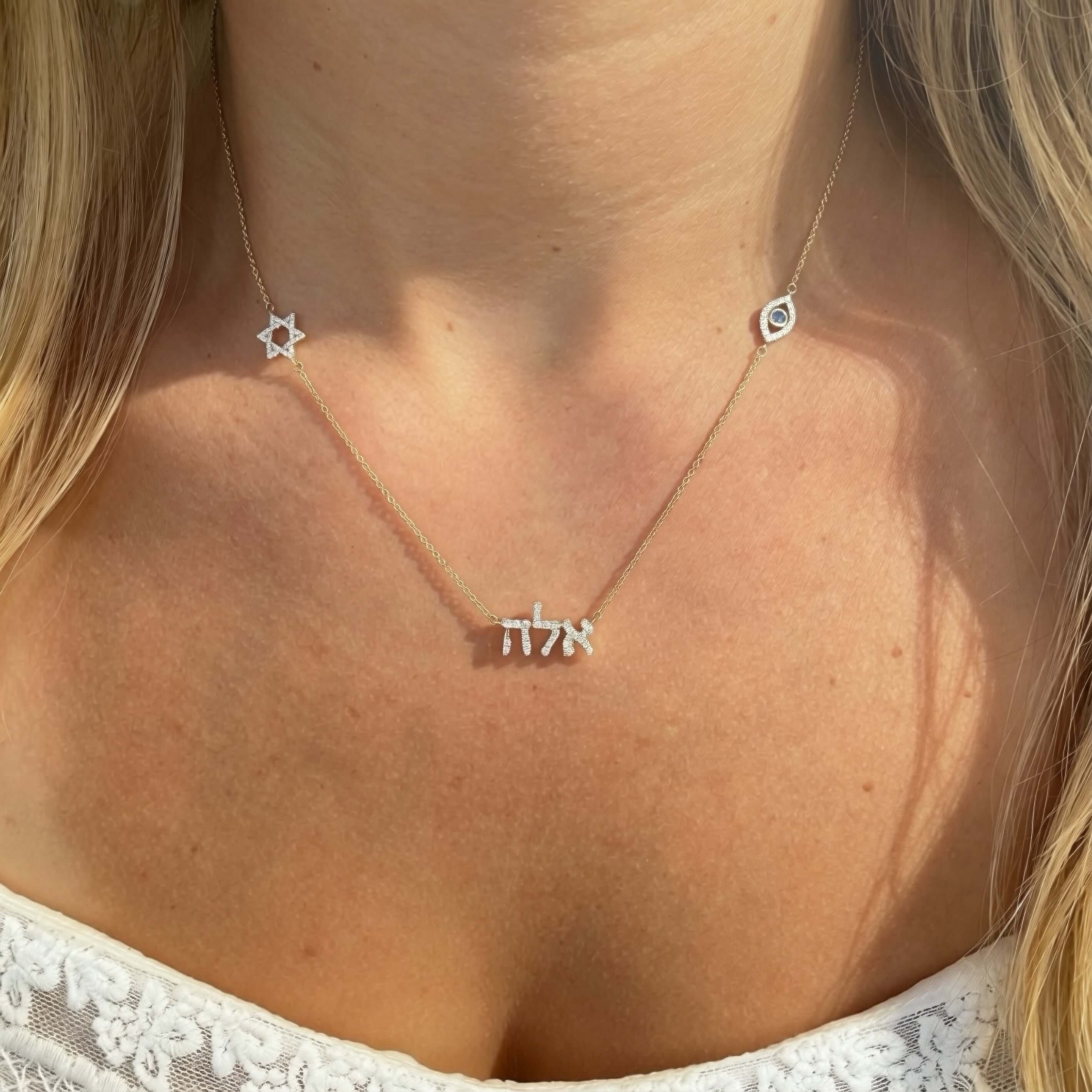 Sacred Symbols Hebrew Name Diamond Necklace displayed on a woman, featuring the Star of David and Evil Eye.