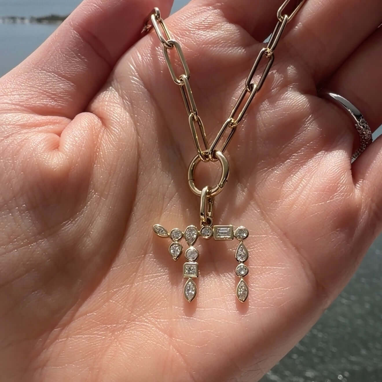 Hebrew Chai Multi Shape Diamond Pendant © showcased on a hand, featuring an array of diamond cuts sparkling in the sunlight.