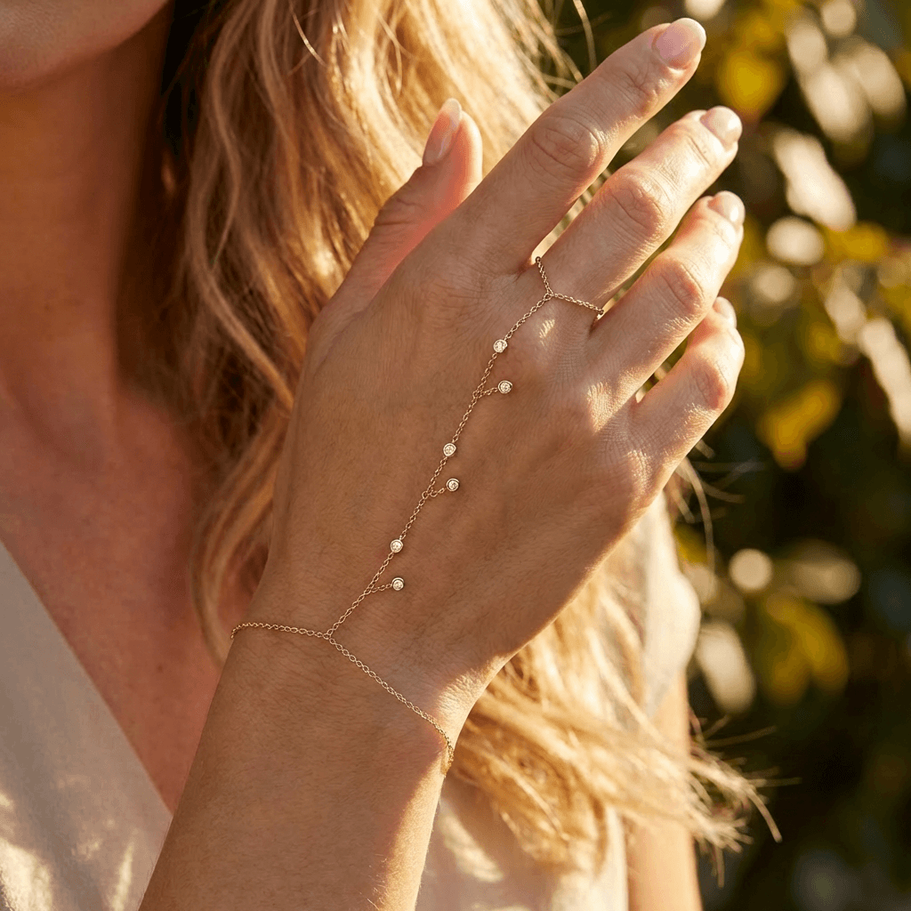 Dangling Bezel-Set Diamond Hand Chain featuring delicate diamonds on a woman's hand in sunlight.