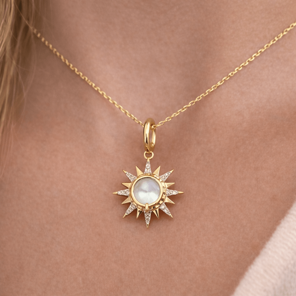 Diamond Sunburst Mother of Pearl Charm worn as a pendant on a gold chain, highlighting its intricate sunburst design and glow.