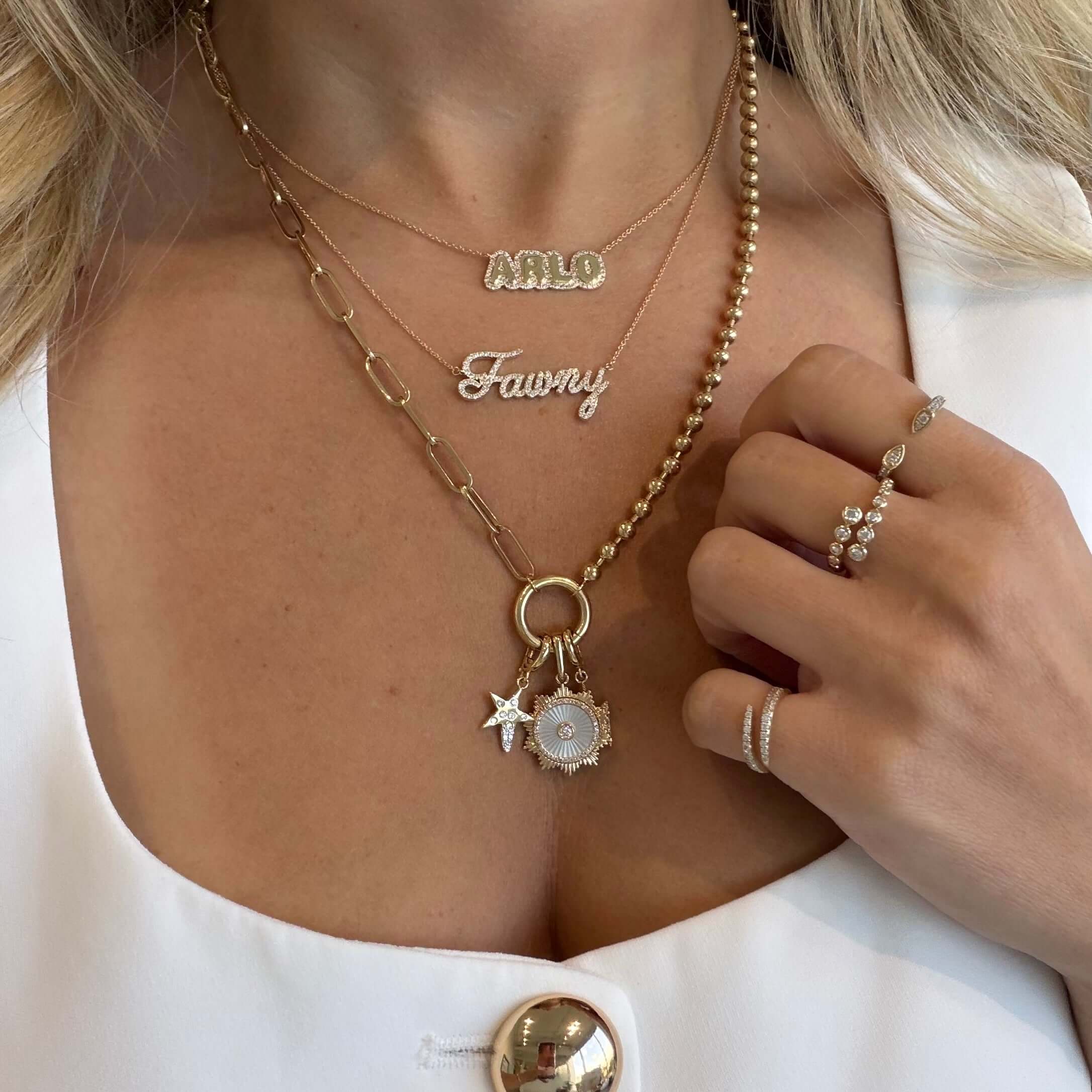 Diamond Bezels Wrap Ring and layered gold necklaces, featuring nameplates and charms, close-up of elegant jewelry style.
