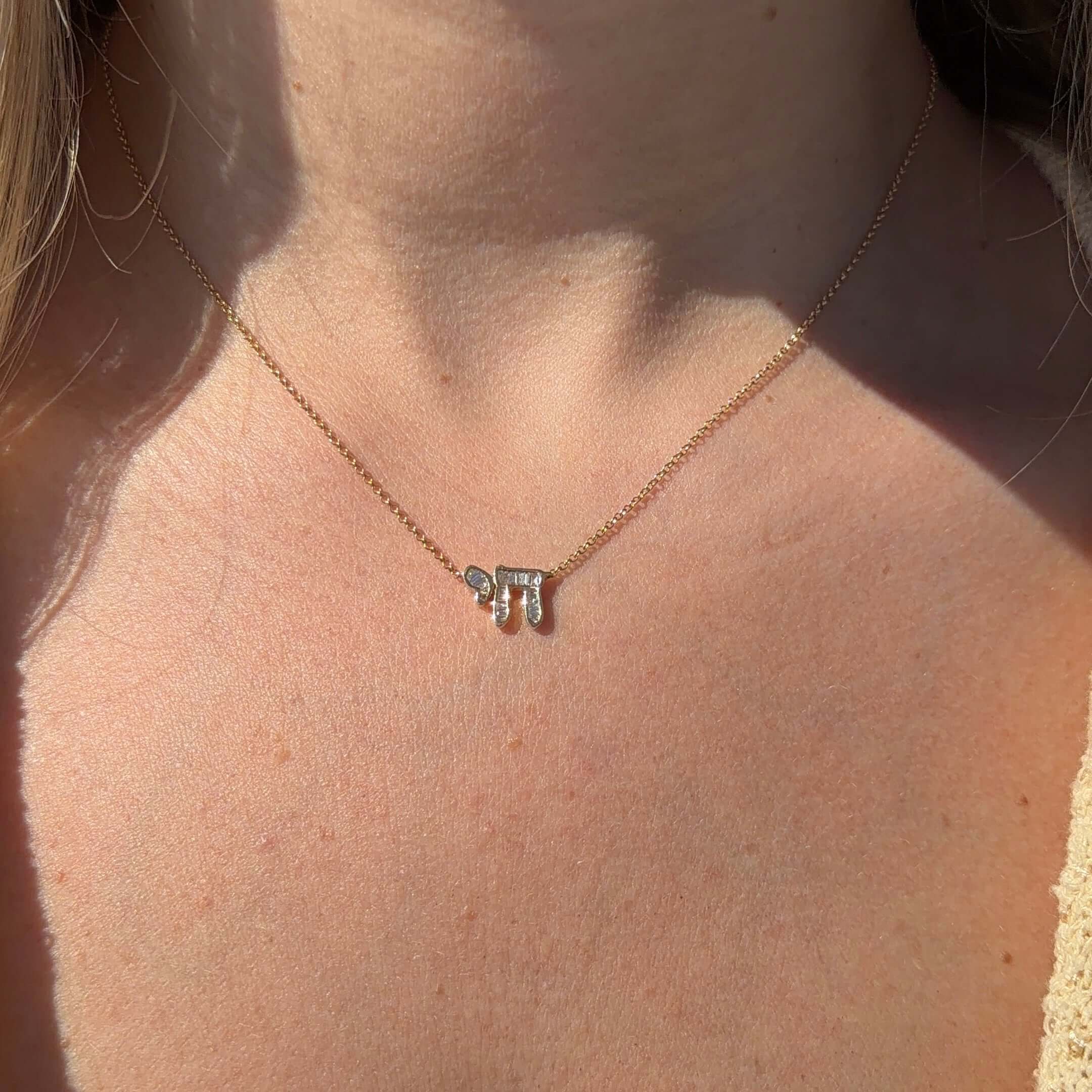 Hebrew Chai Baguette Diamond Necklace displayed on a model, gleaming in 14K gold with shiny baguette diamonds.