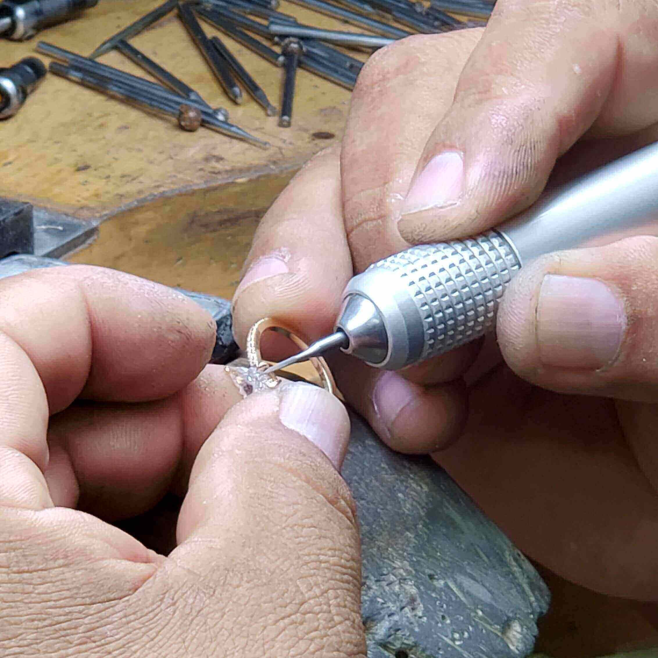 Craftsman working meticulously on a fine jewelry piece at Izakov Fine Jewelry, showcasing expert hands and tools.