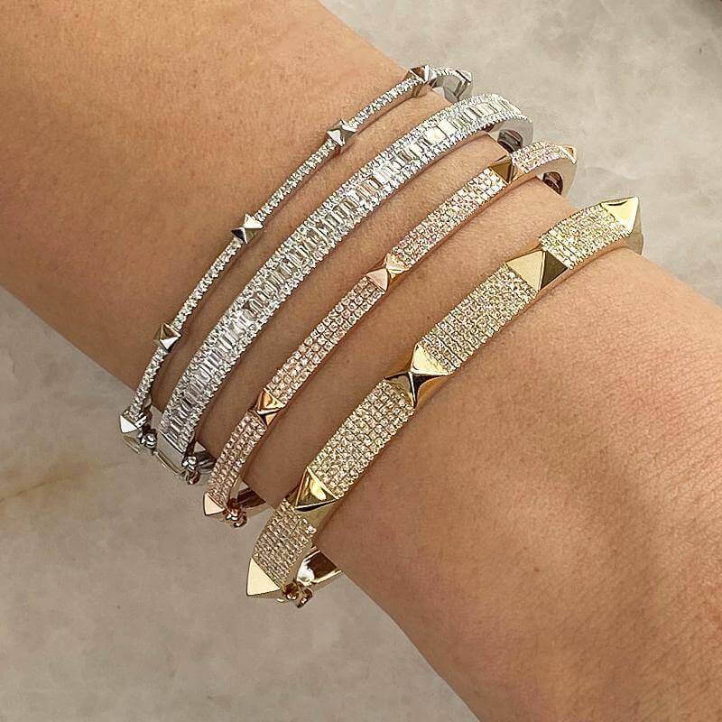 Stylish stack of luxurious silver and gold spike bracelets on wrist, showcasing the elegance and brilliance of our exclusive jewelry collection.