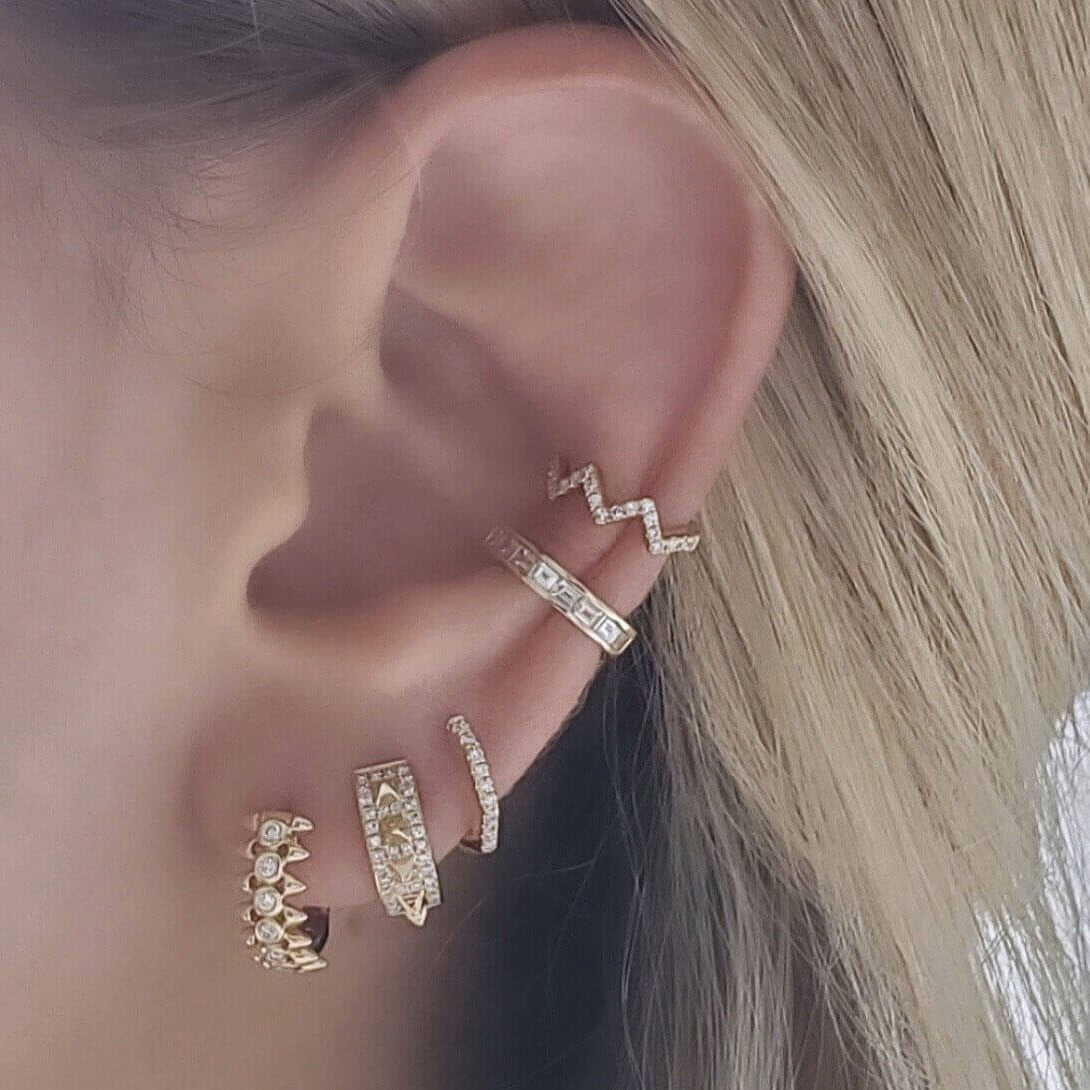 Woman wearing multiple gold and diamond earrings from our jewelry brand