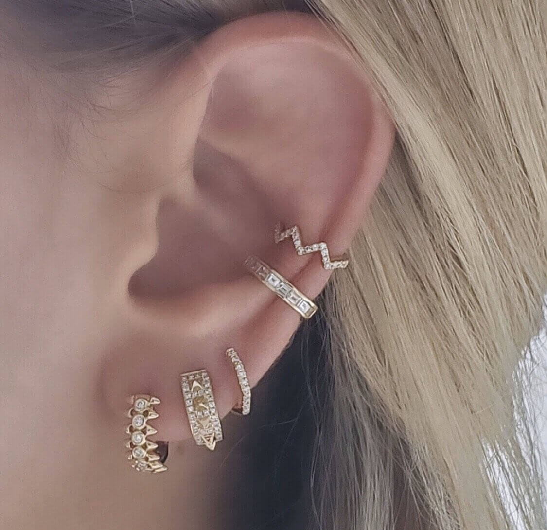 Woman wearing multiple gold and diamond earrings from our jewelry brand