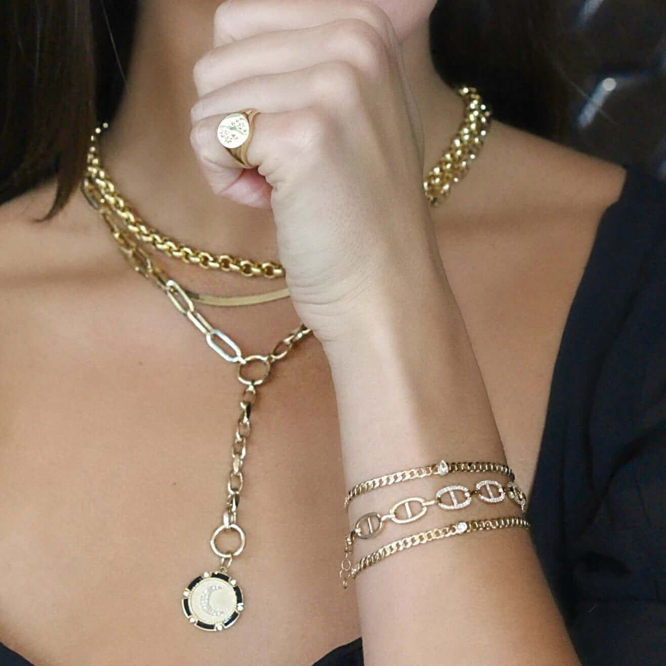 Woman wearing gold jewelry set including layered necklaces, chain bracelet, and ring from our luxury jewelry brand.