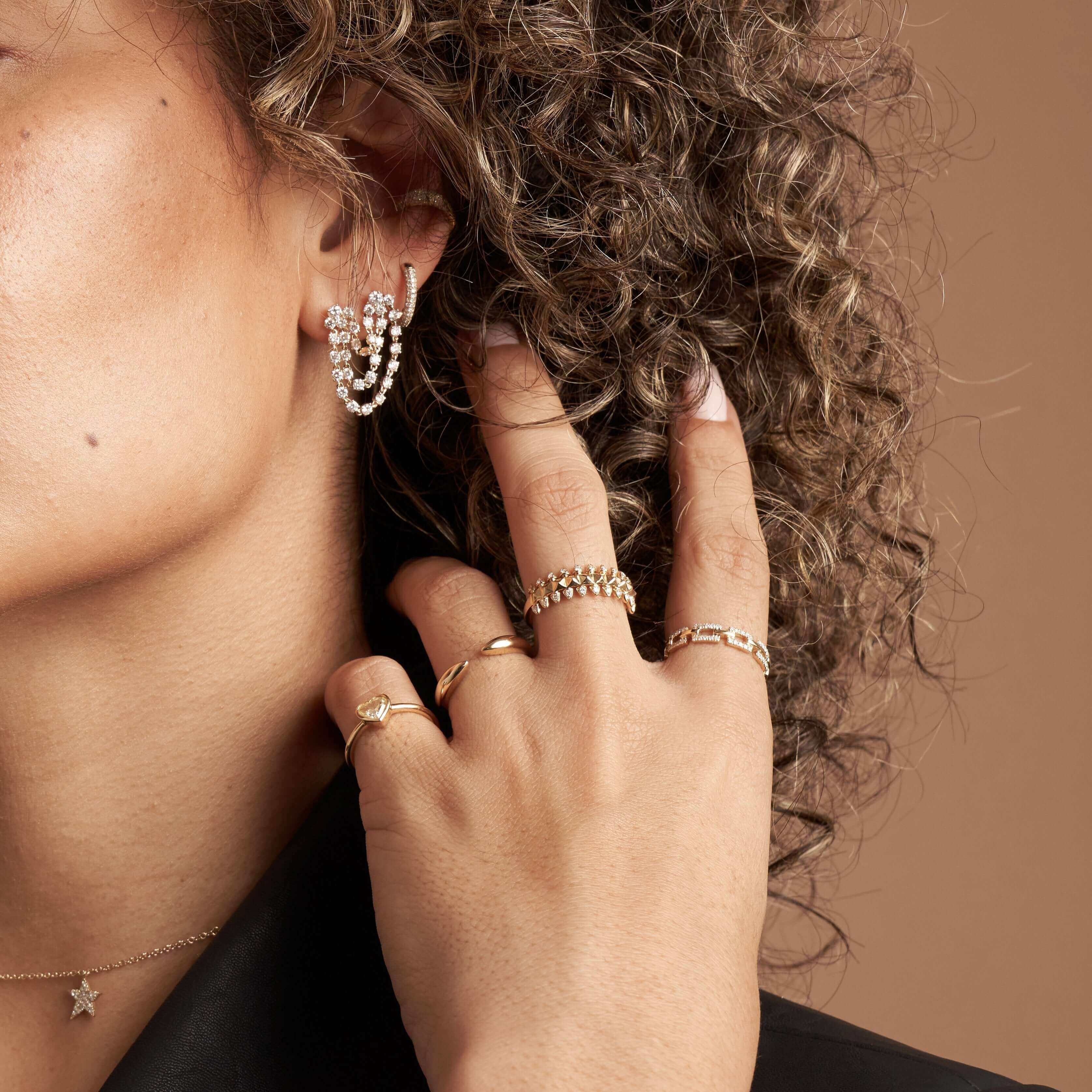 Woman showcasing elegant gold rings and pearl drop earrings from our jewelry collection, highlighting minimalist luxury fashion.