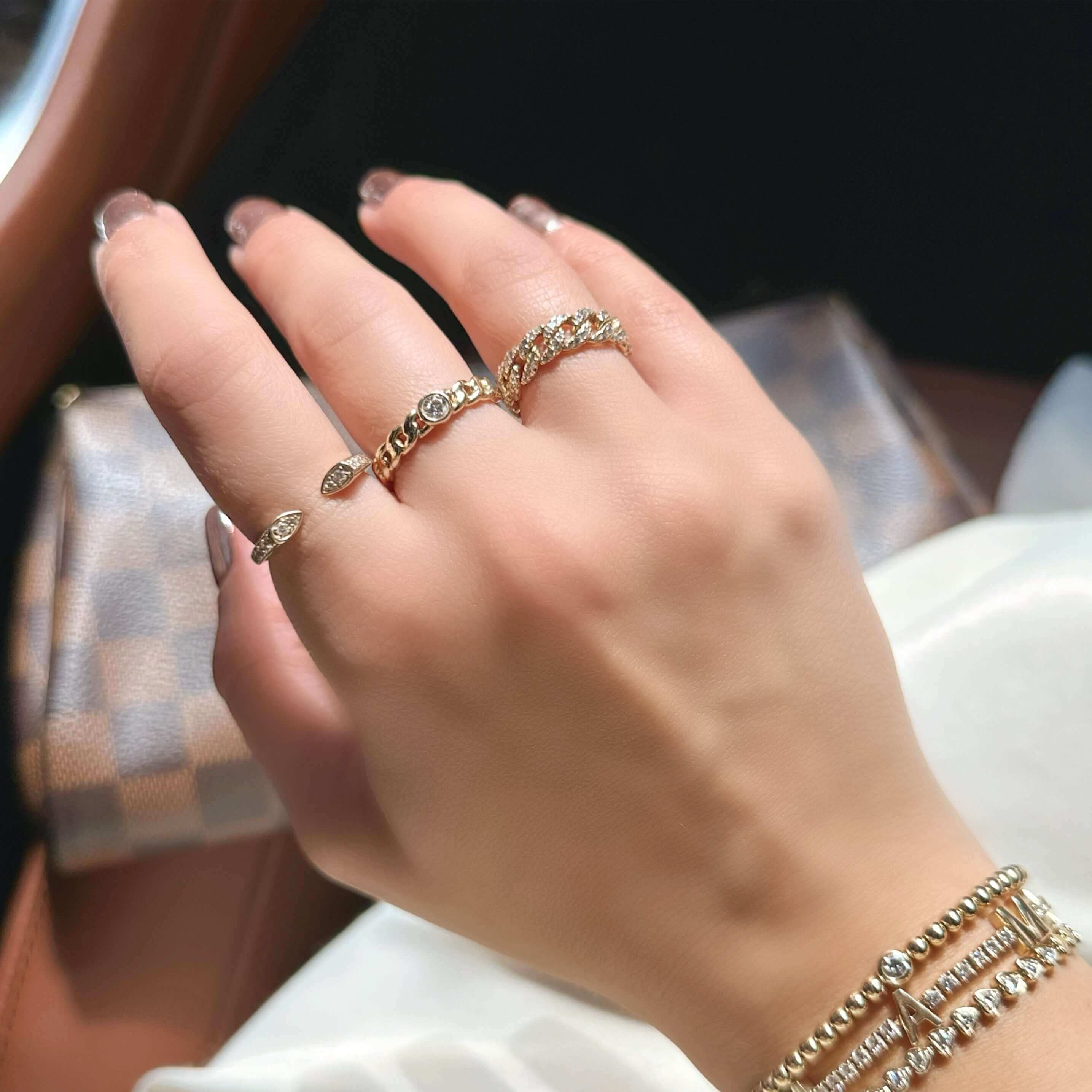 Woman's hand adorned with elegant gold rings and matching beaded bracelets, enhancing the luxurious appeal of our jewelry brand.
