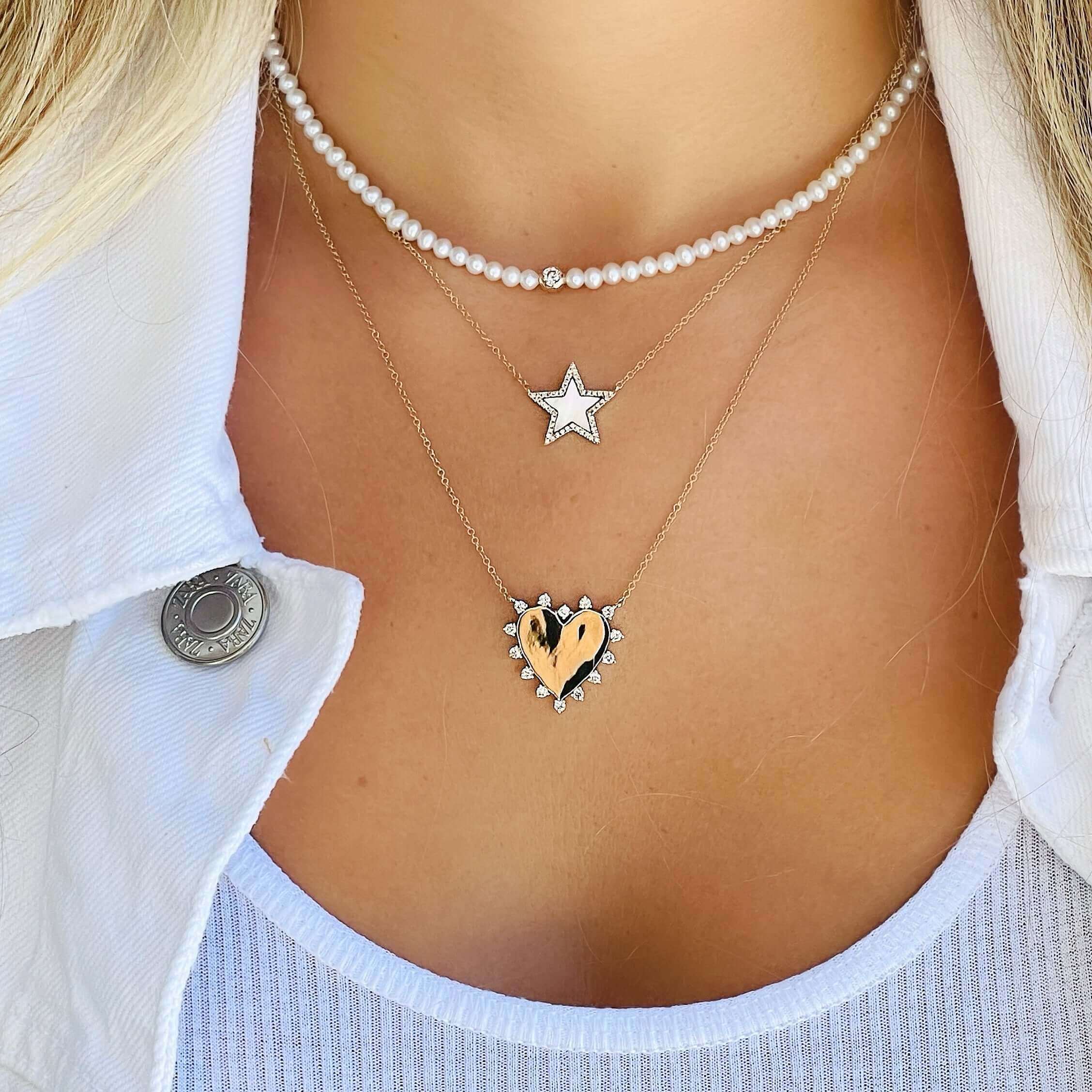 Woman wearing layered heart and star necklaces from our jewelry collection