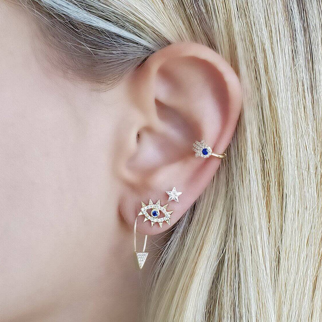 Diamond Accented Spikes Evil Eye Button Earrings worn on an ear, showcasing the beautiful sapphire center and diamond accents.
