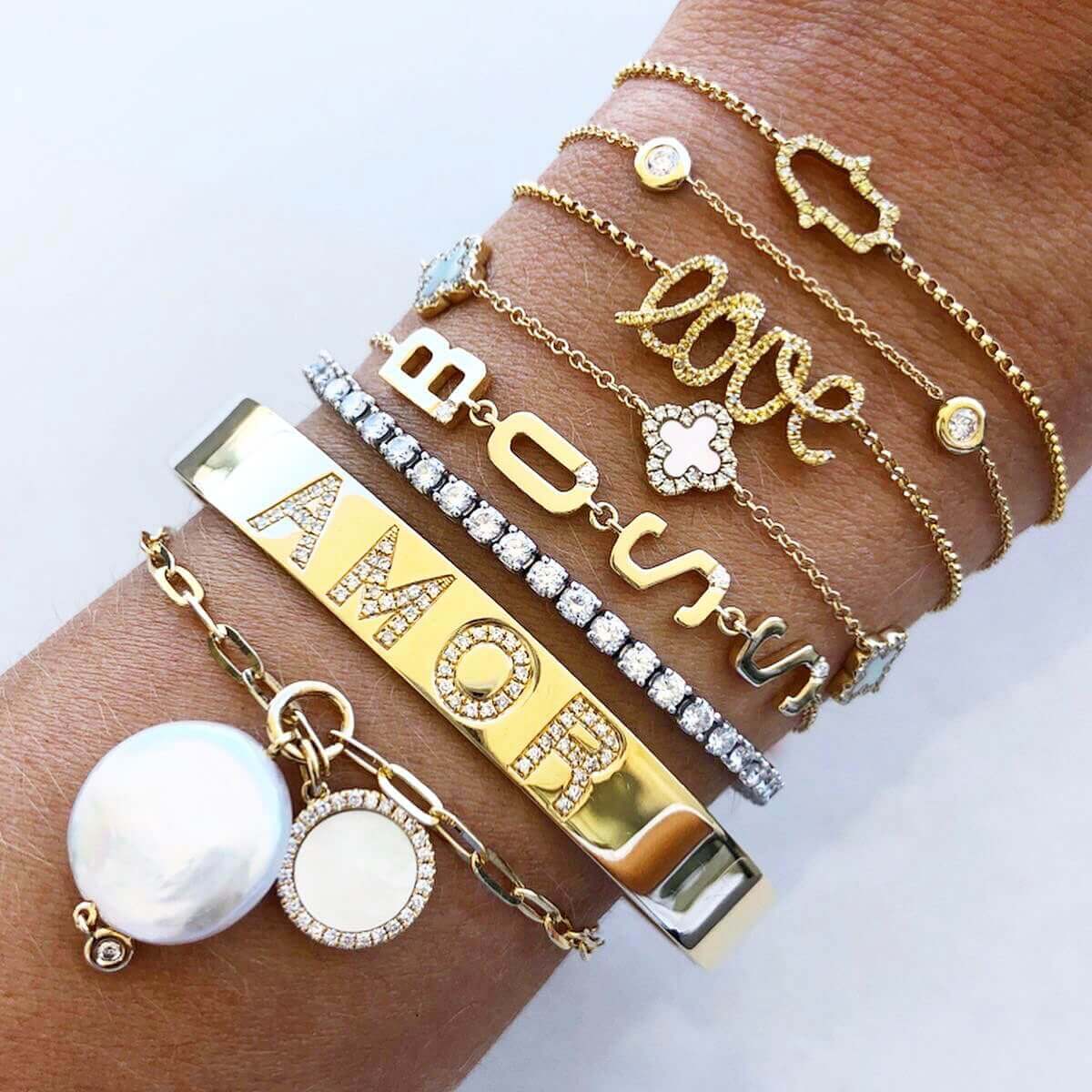 Elegant gold and diamond bracelets showcasing 'AMOR' and 'LOVE' designs with a pearl accent, perfect for adding a touch of luxury.