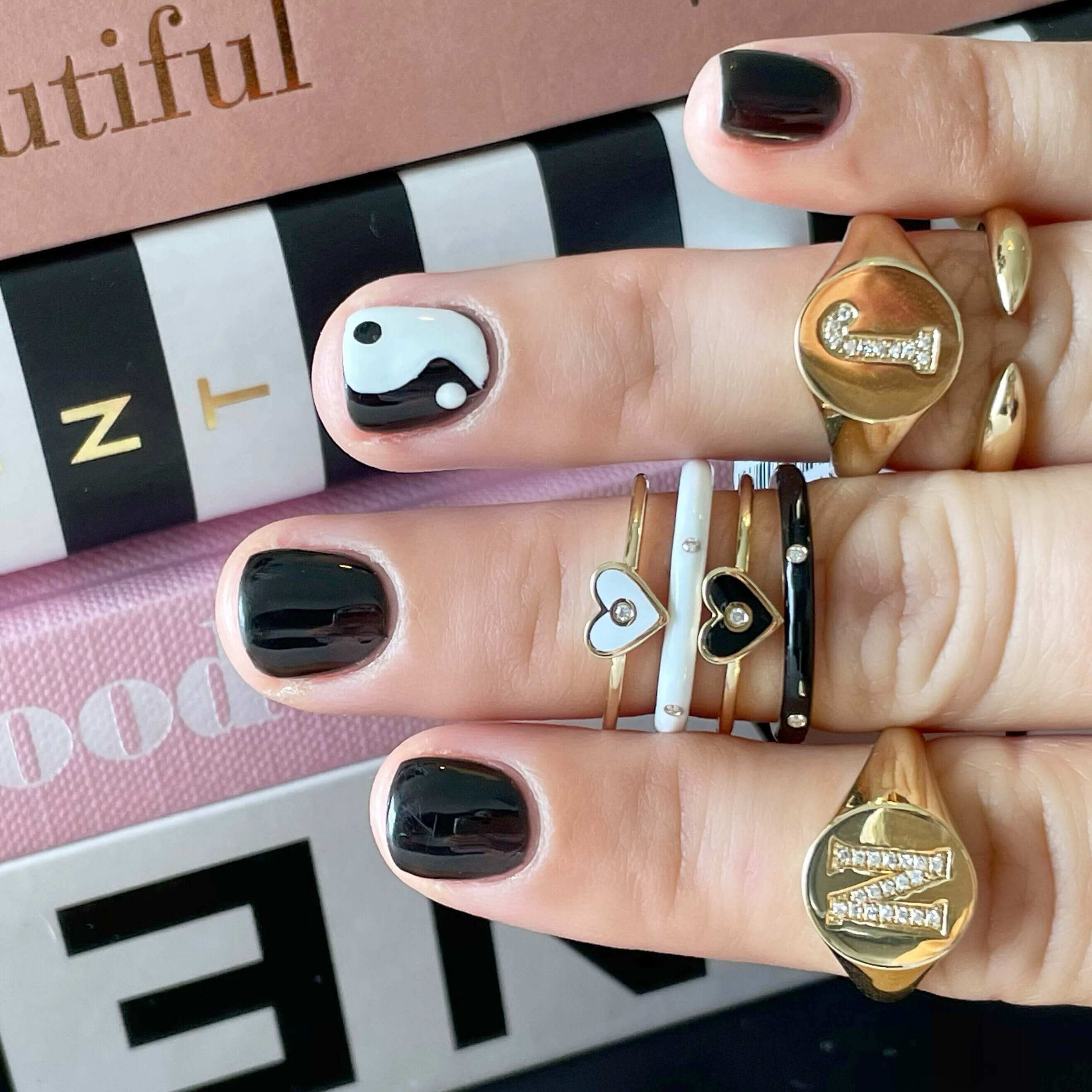 Stylish gold and silver heart rings paired with black nail polish from our exclusive jewelry collection.