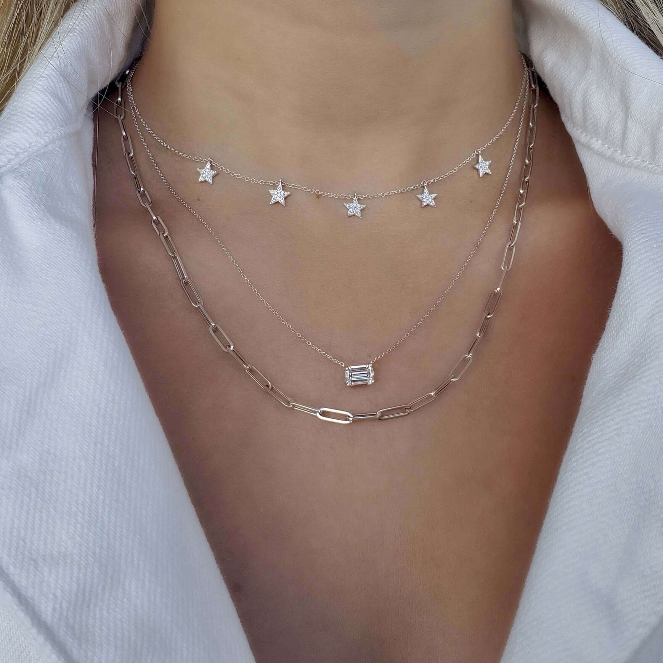 Layered necklaces featuring star charms and a rectangular pendant on a woman's neck, perfect for elegant and stylish jewelry lovers.