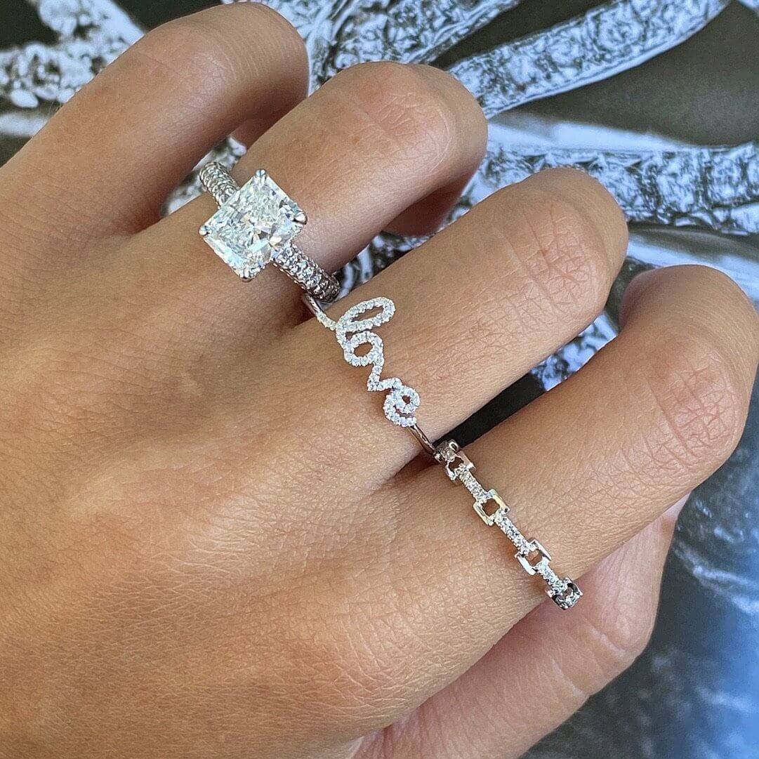 Elegant diamond and "love" script rings from our jewelry brand displayed on hand