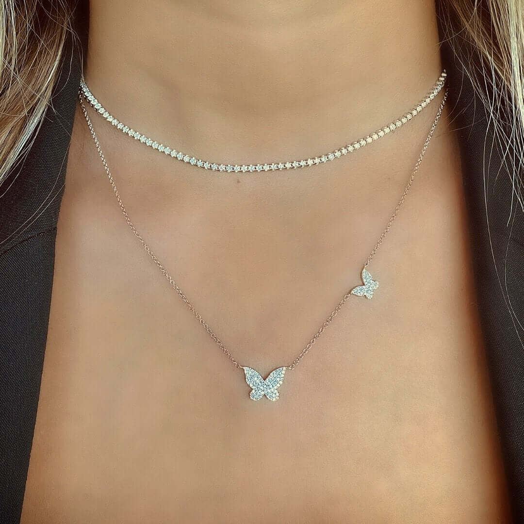 Diamond Pave Papillon Butterflies Duo Necklace showcased on a model, featuring two sparkling butterfly charms in 14k gold.