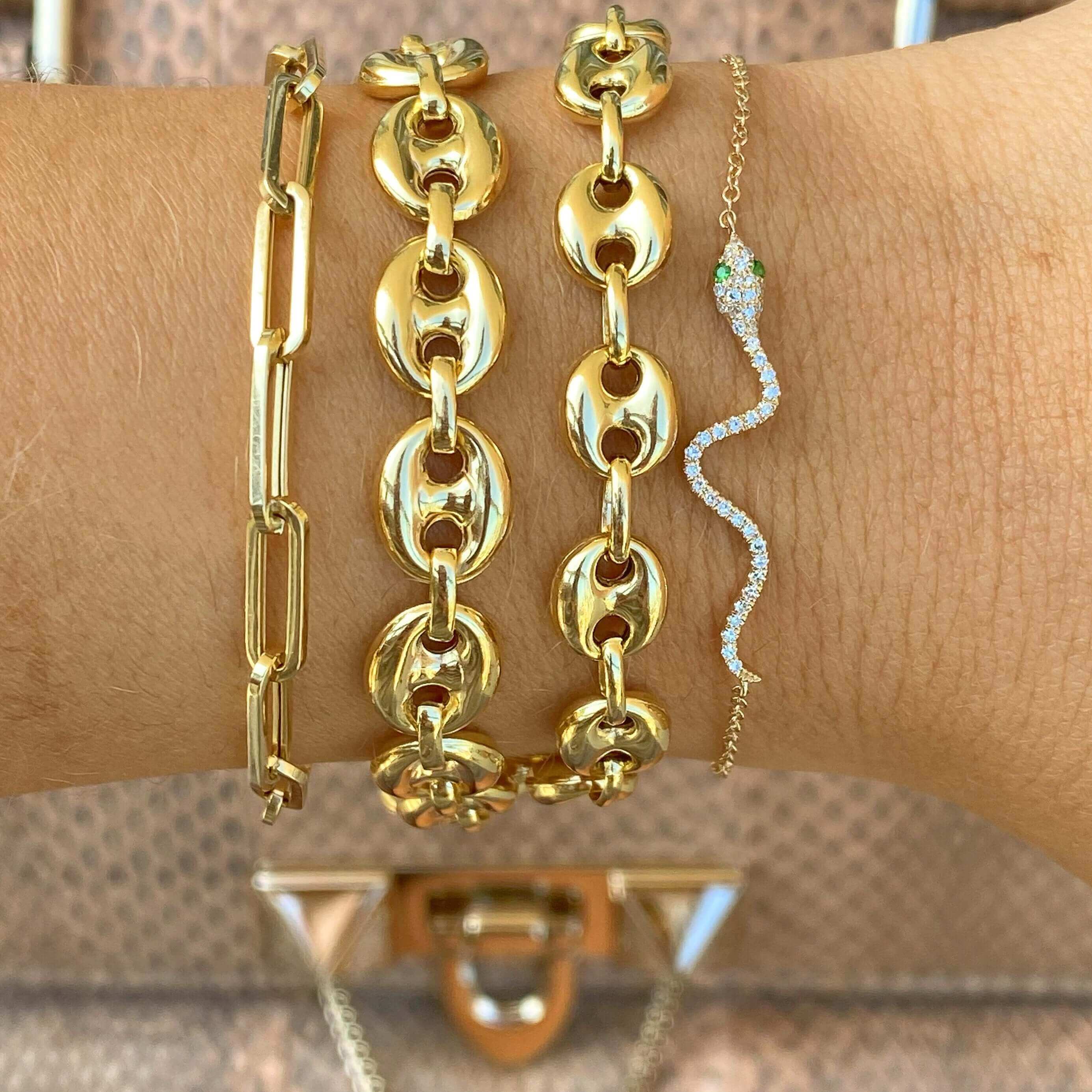 Gold chain bracelets and a delicate snake-shaped diamond bracelet on wrist