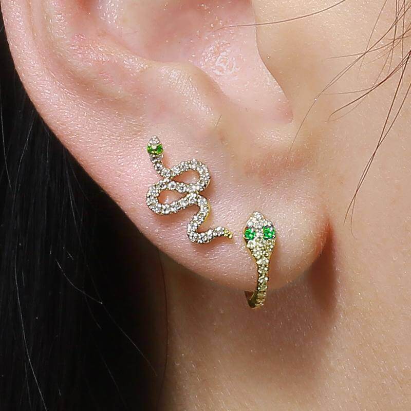 Snake-shaped gold and diamond earrings with emerald accents from our luxury jewelry collection, worn on ear.