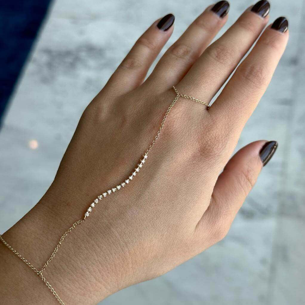 Elegant gold hand chain bracelet with delicate diamond accents on a woman's hand, perfect for adding a touch of luxury to your jewelry collection.