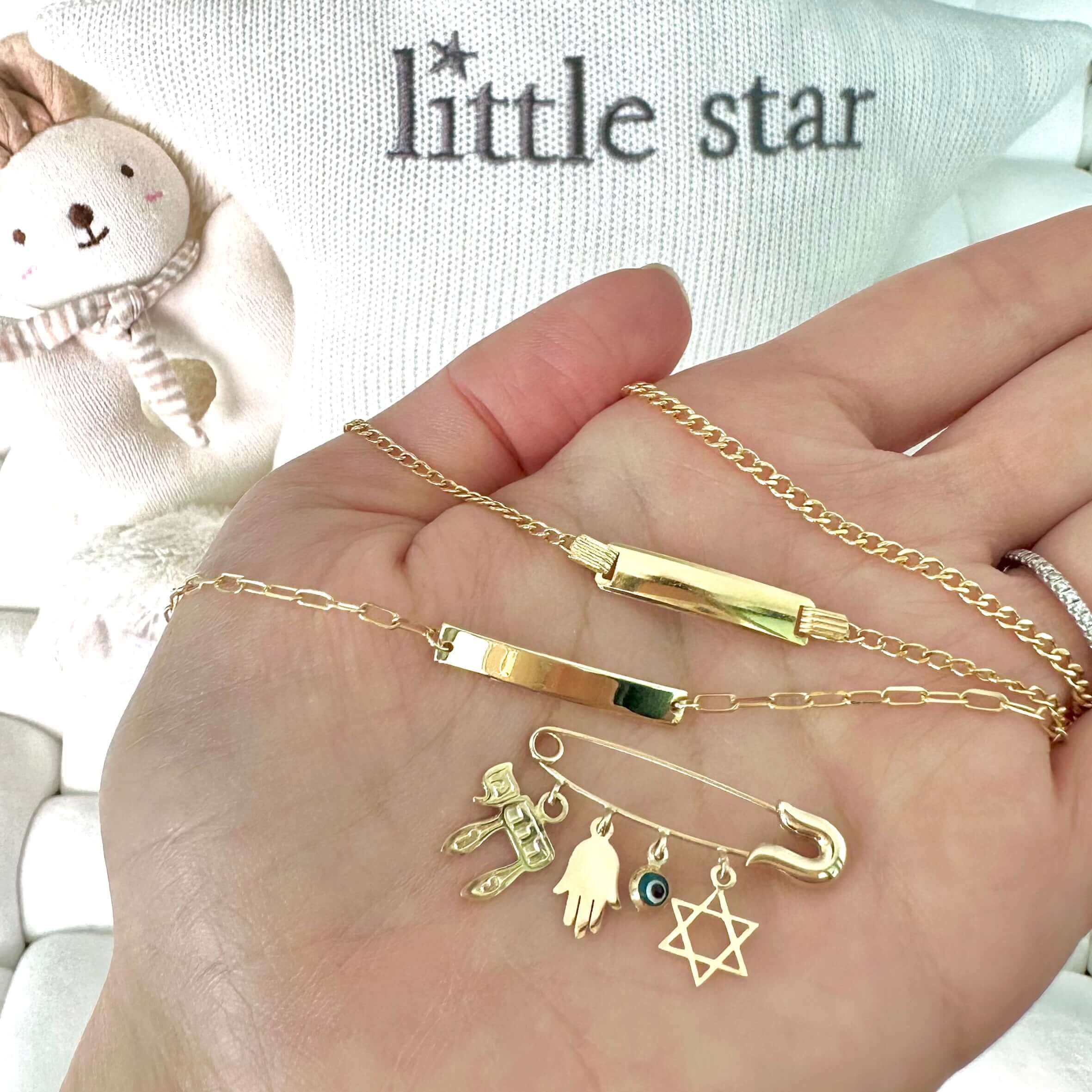 Gold delicate jewelry collection from Little Star, featuring charm bracelets and necklaces held in an open palm
