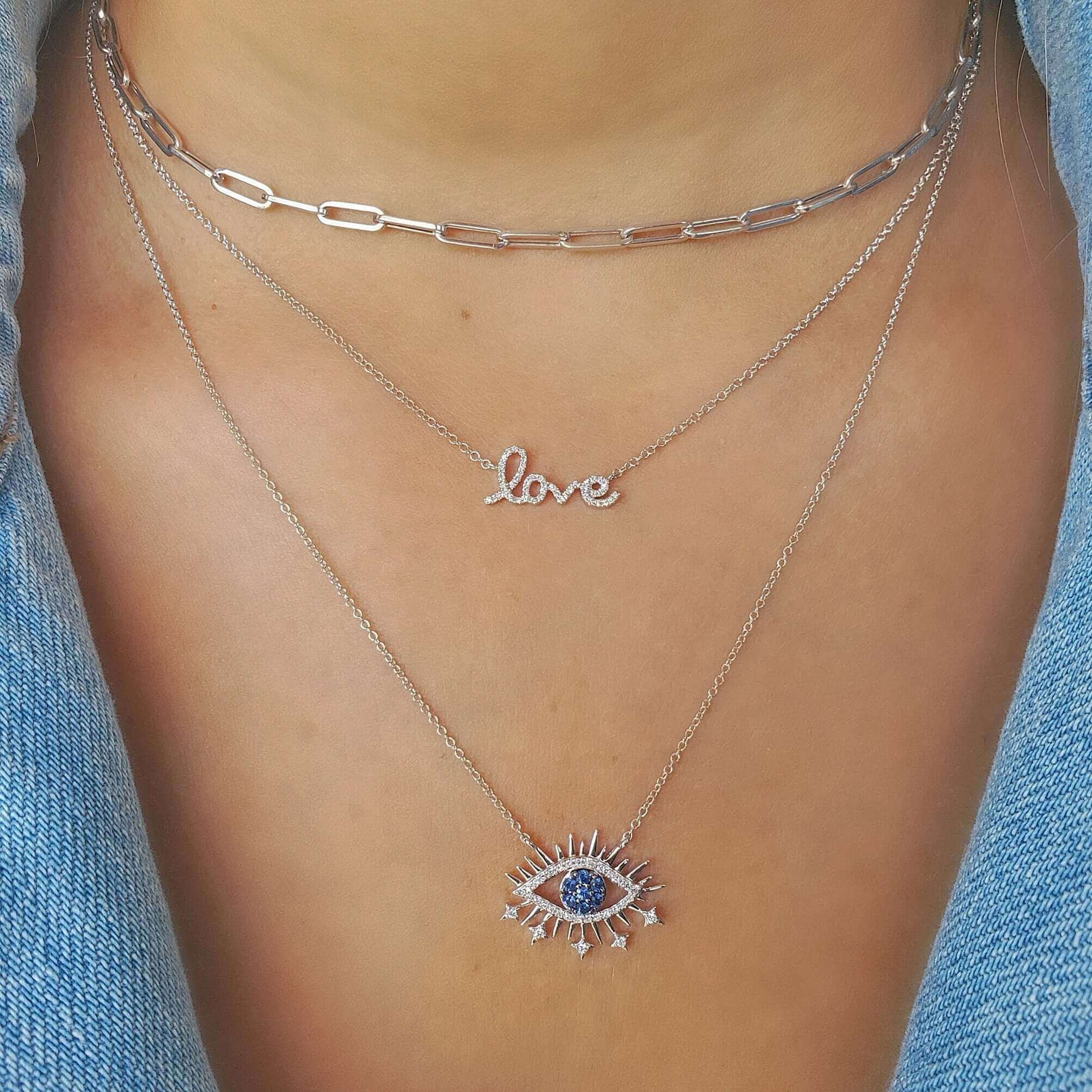 Layered silver necklaces with "love" charm and eye pendant from our jewelry collection.