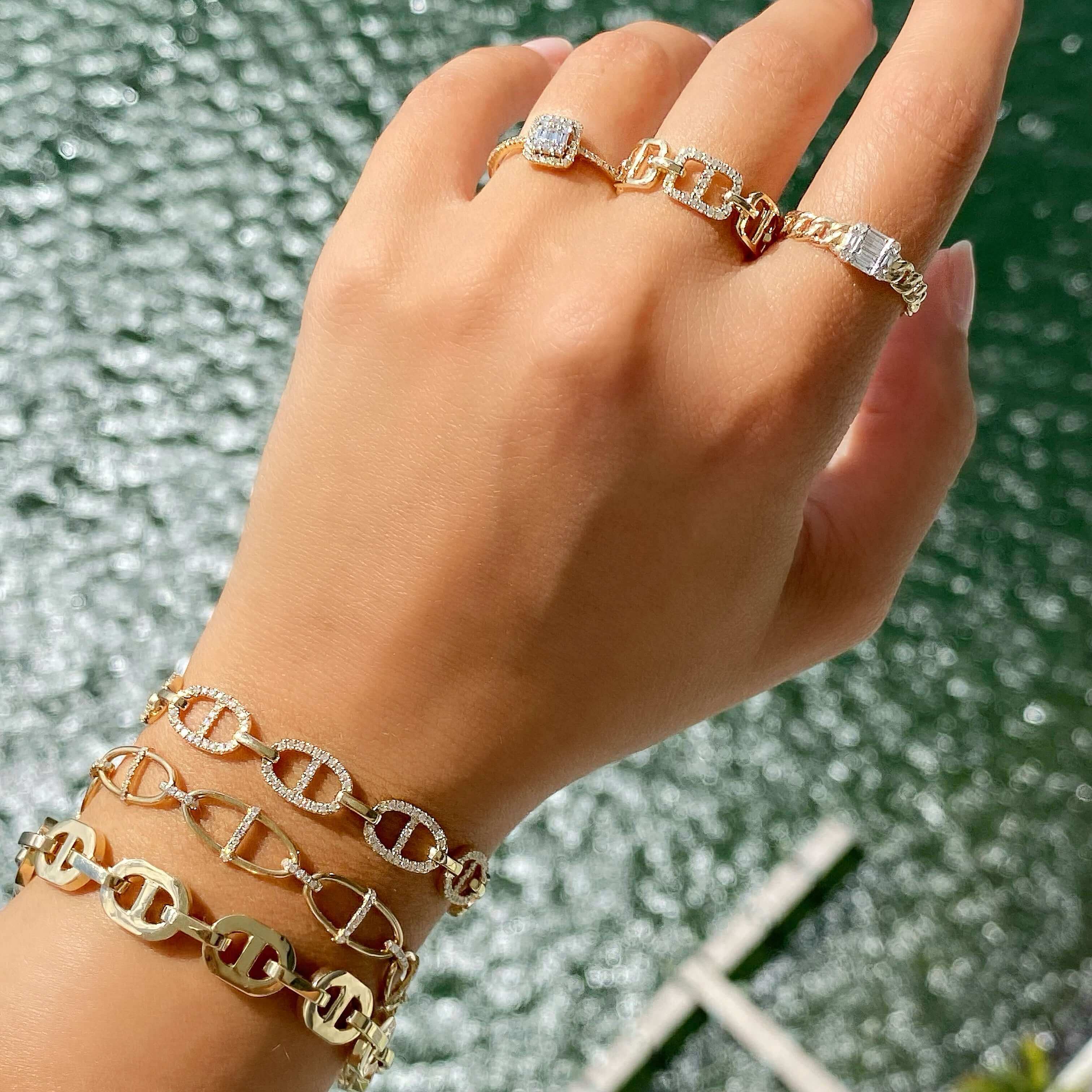 Elegant gold and silver jewelry on hand featuring bracelets and rings by our premium jewelry brand, showcased against a scenic water backdrop