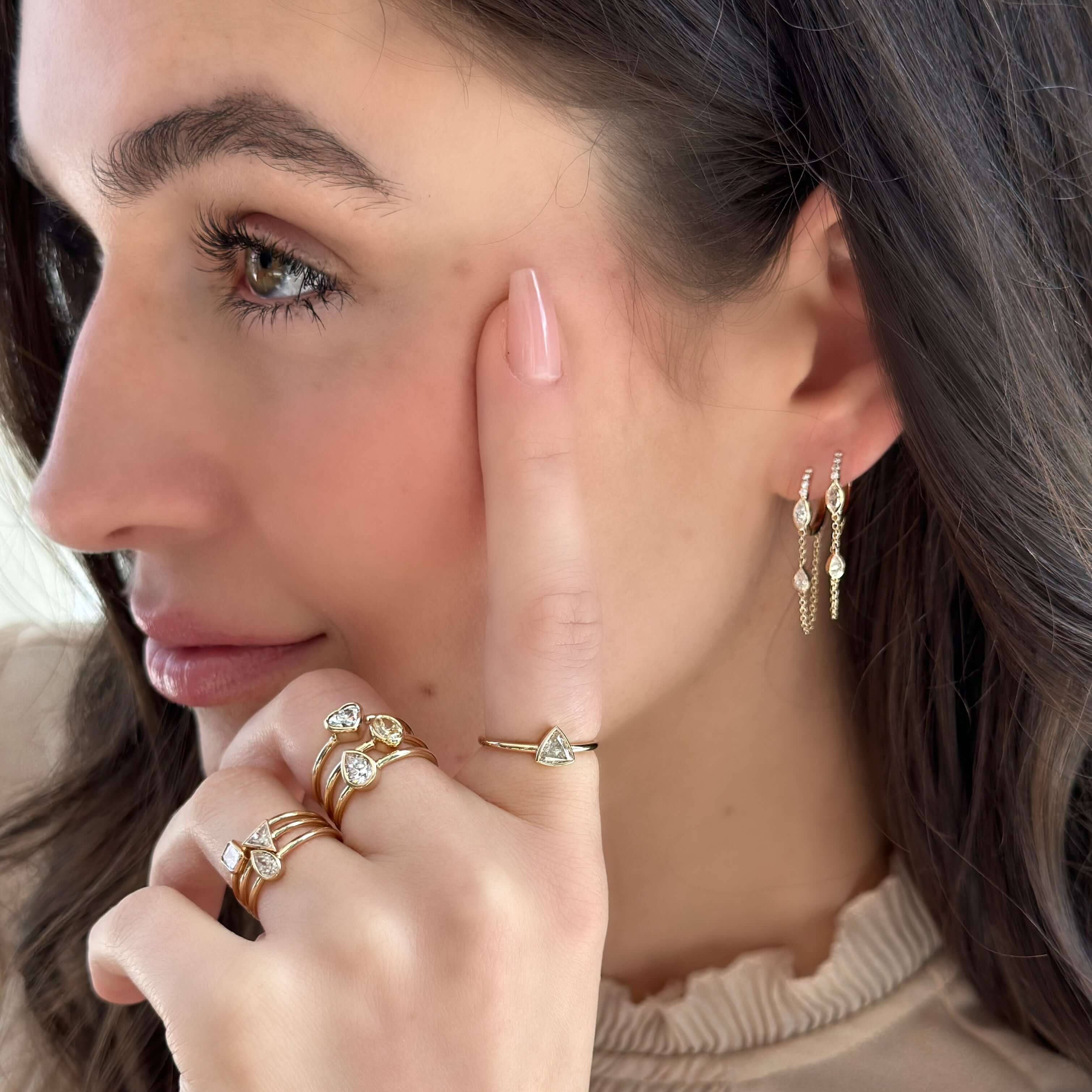 Woman wearing elegant gold earrings and matching rings from our jewelry brand