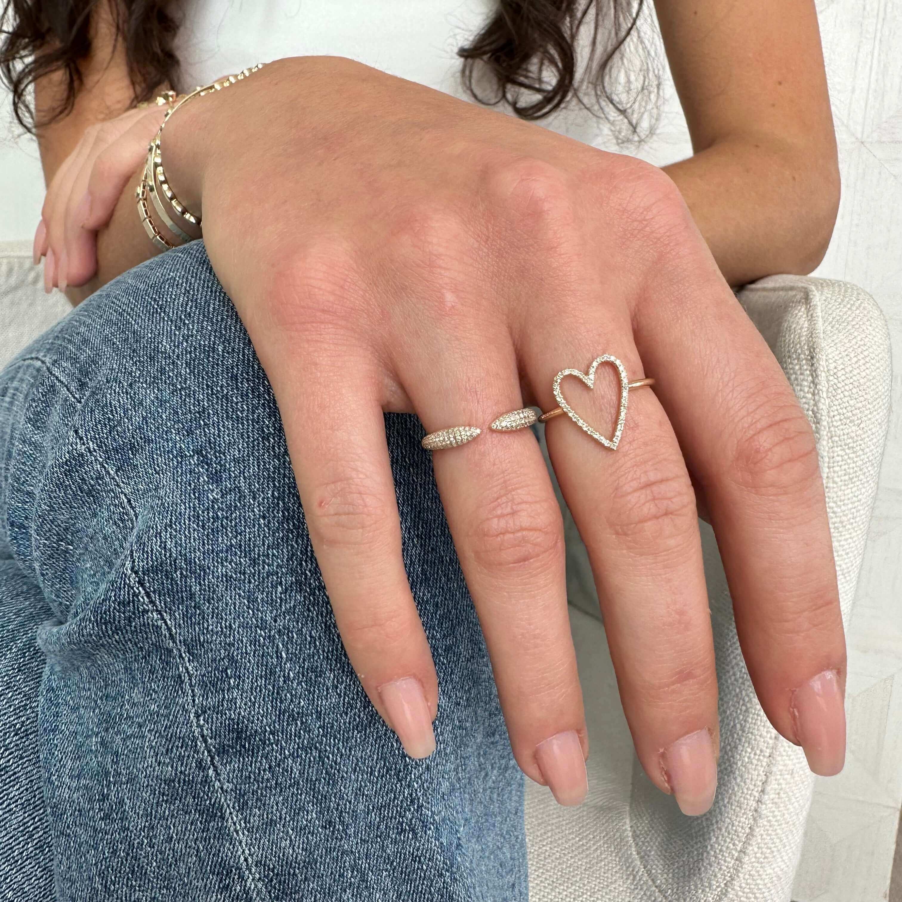Woman's hand accessorized with a heart-shaped diamond ring and a thin band ring from our luxury jewelry collection.