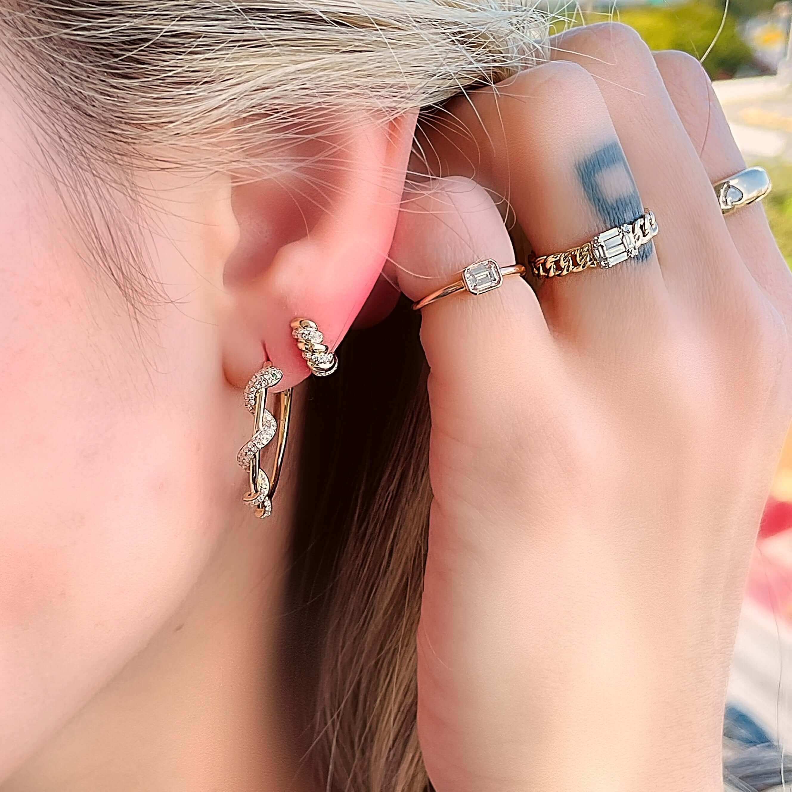 Woman showcasing elegant hoop earrings and dainty gold rings from our jewelry collection.