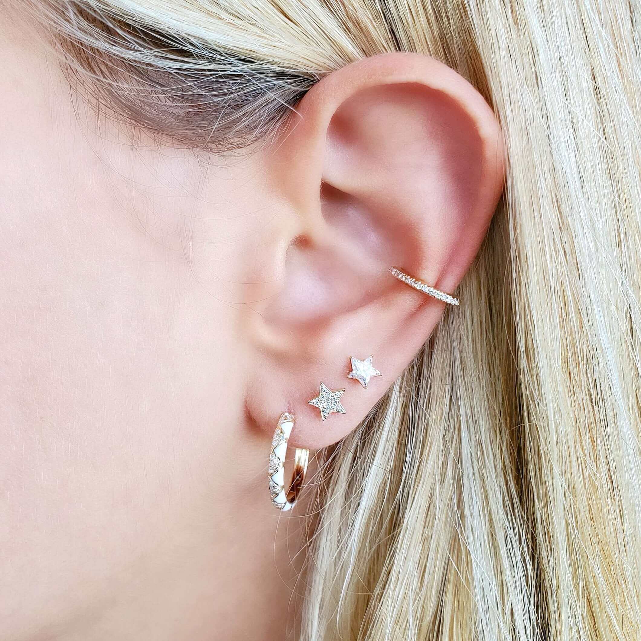 Woman wearing sparkling star-shaped earrings and a textured hoop, showcasing modern jewelry from our elegant collection.