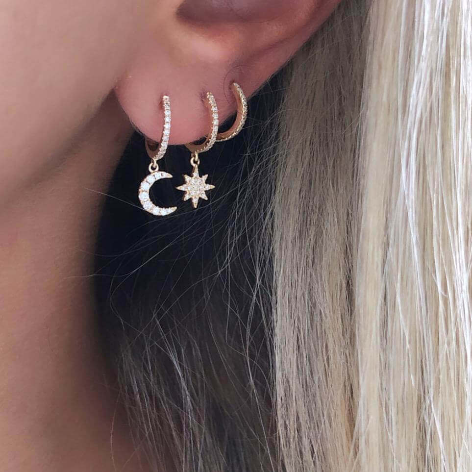 Woman wearing gold celestial moon and star dangle earrings.