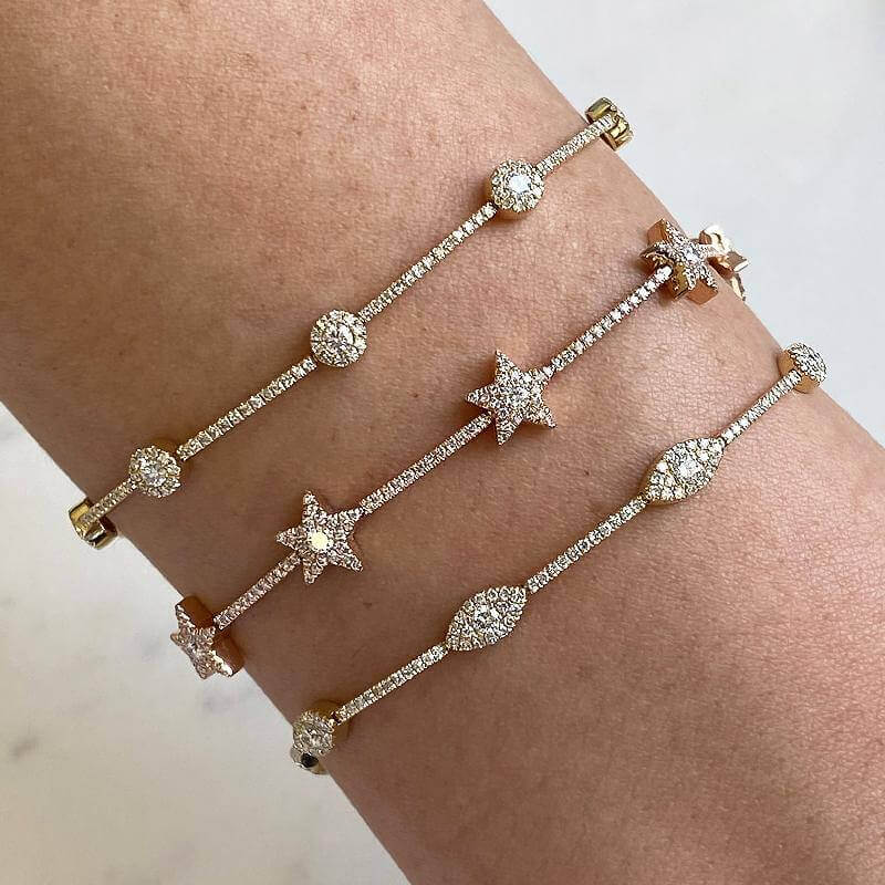 Three diamond-studded bracelets with celestial designs on wrist, part of our luxury jewelry collection.