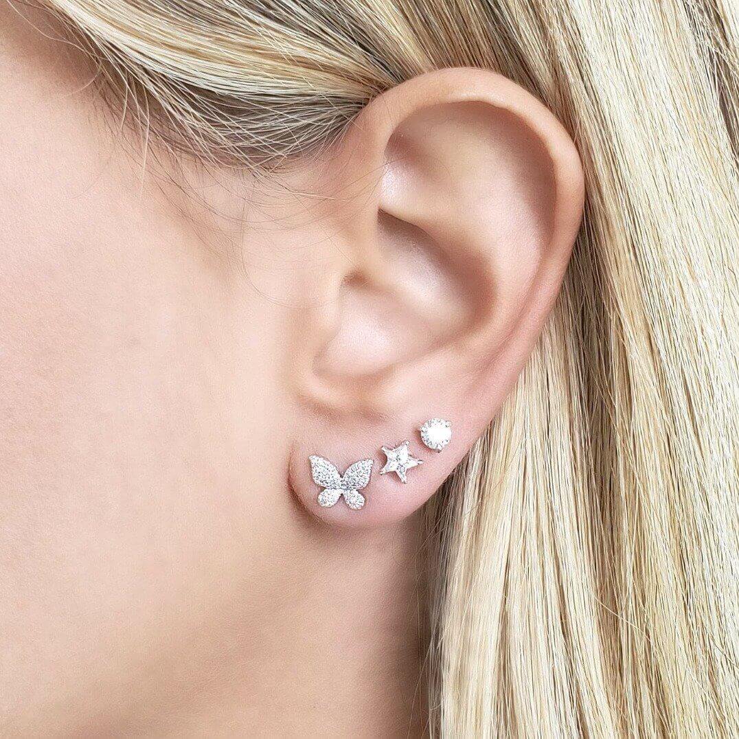 Woman wearing gold butterfly, star, and stud earrings for a stylish, elegant look