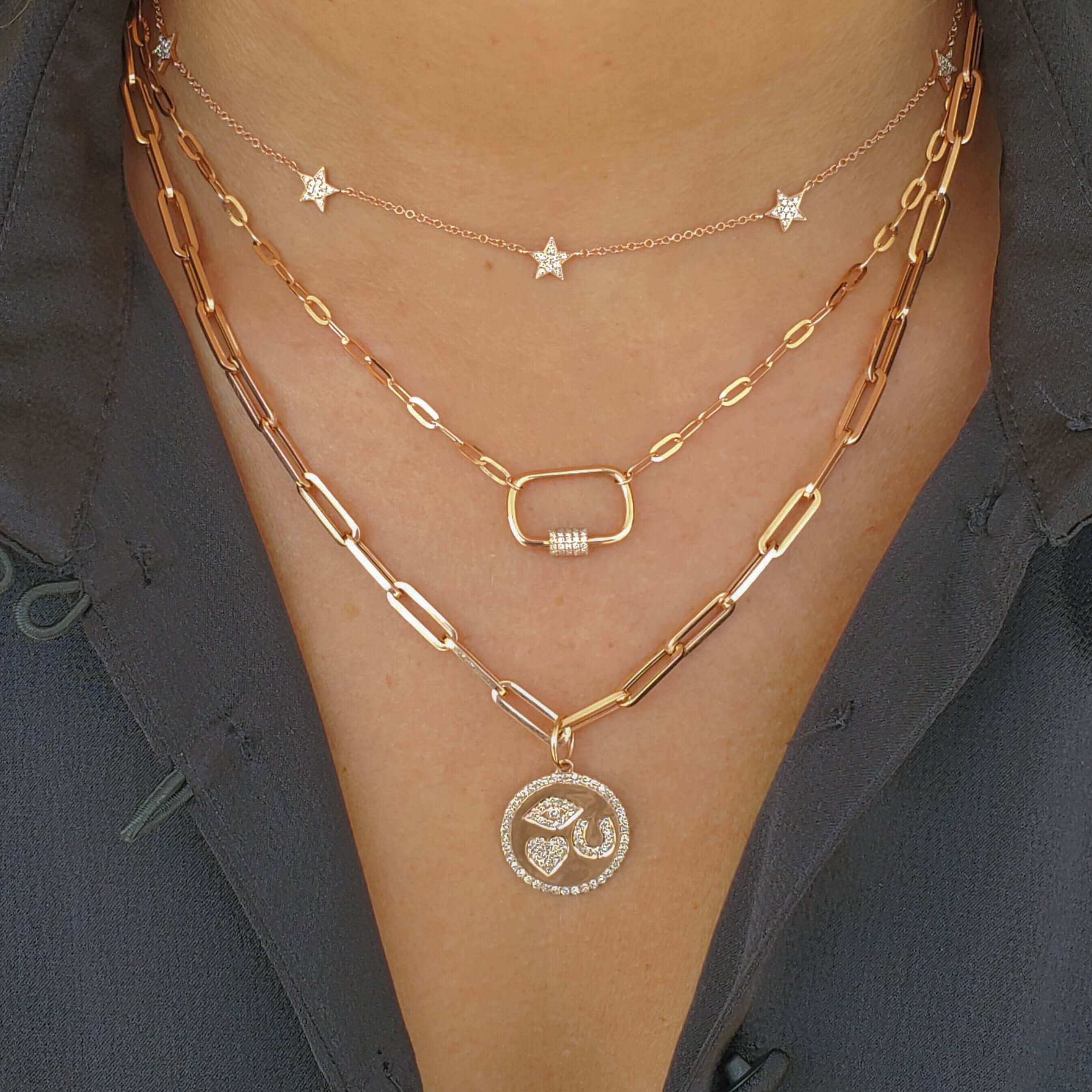 Woman wearing layered gold necklaces with star pendant and circular charm, showcasing elegant jewelry from our luxury brand collection.