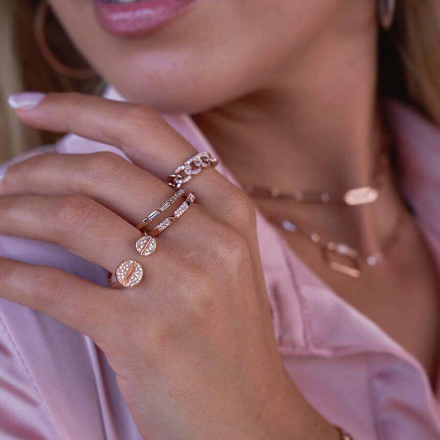 Close-up of an elegant woman wearing rose gold rings and necklace showcasing our jewelry brand's intricate designs.