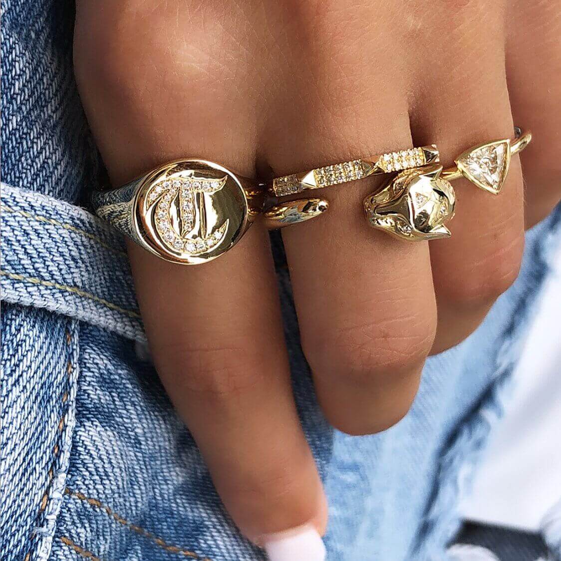 Gold signature rings with intricate designs on a hand, highlighting our jewelry brand's luxurious craftsmanship and style.