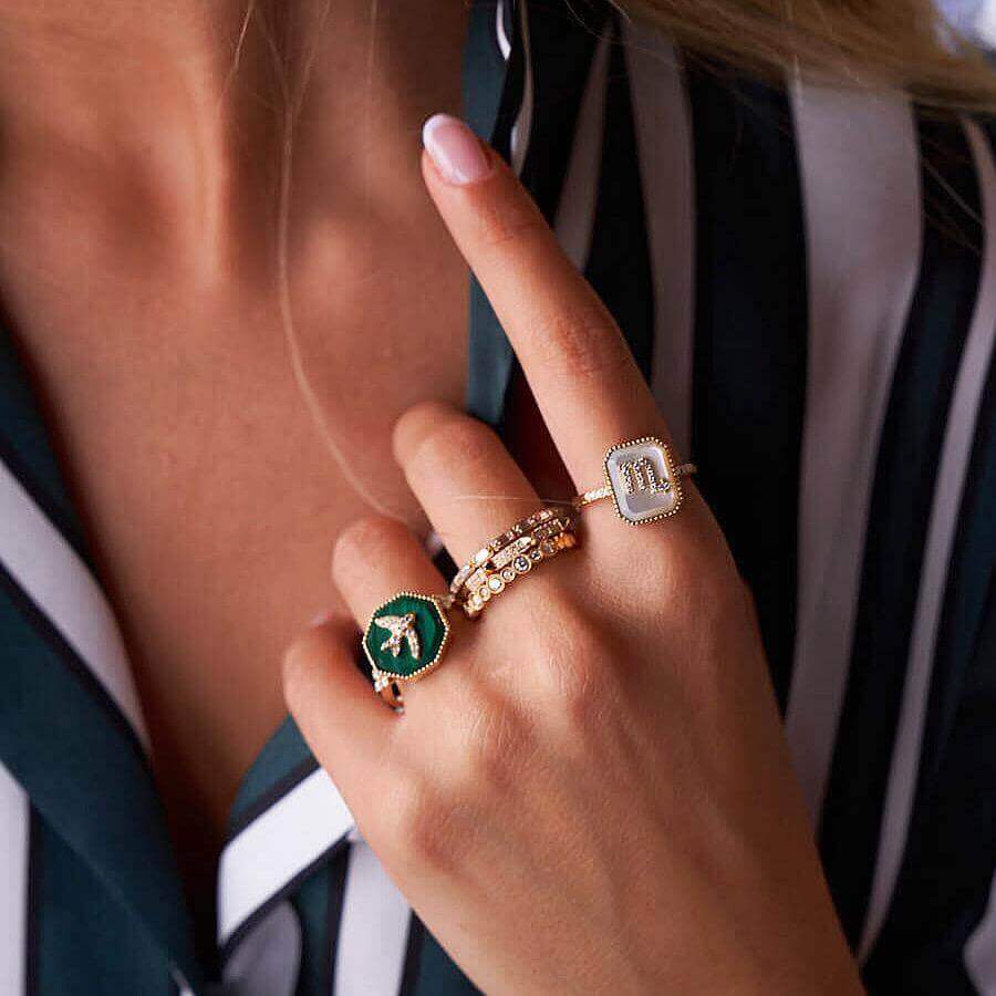 Woman wearing luxury gold letter rings by our jewelry brand, featuring elegant designs and sparkling stones.