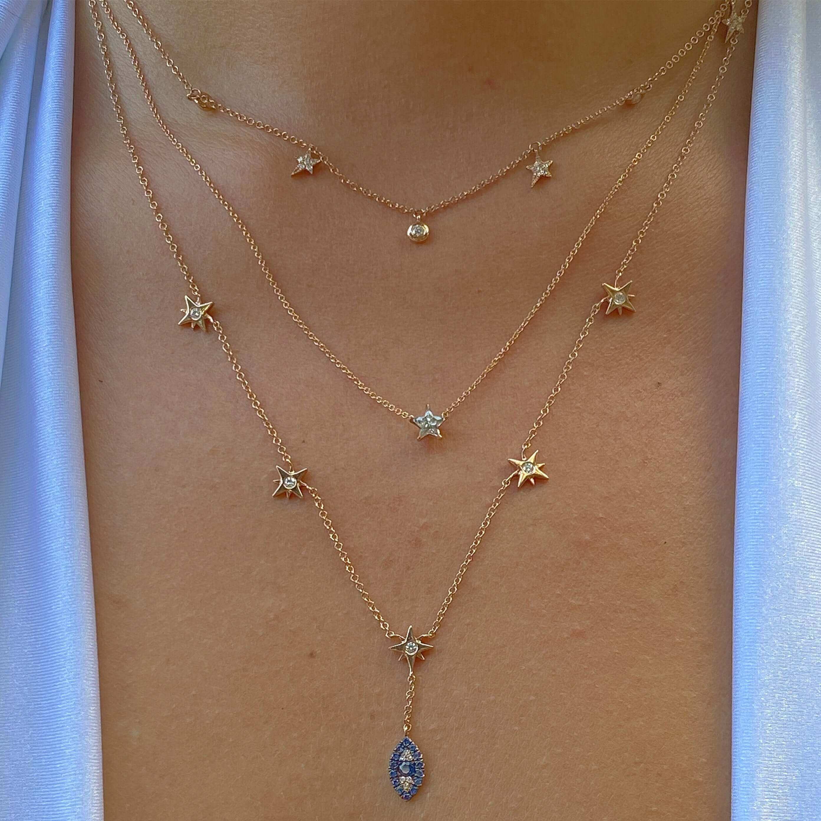Layered gold necklaces with star and gem pendants displayed on a person's neck, highlighting elegant jewelry from our brand.
