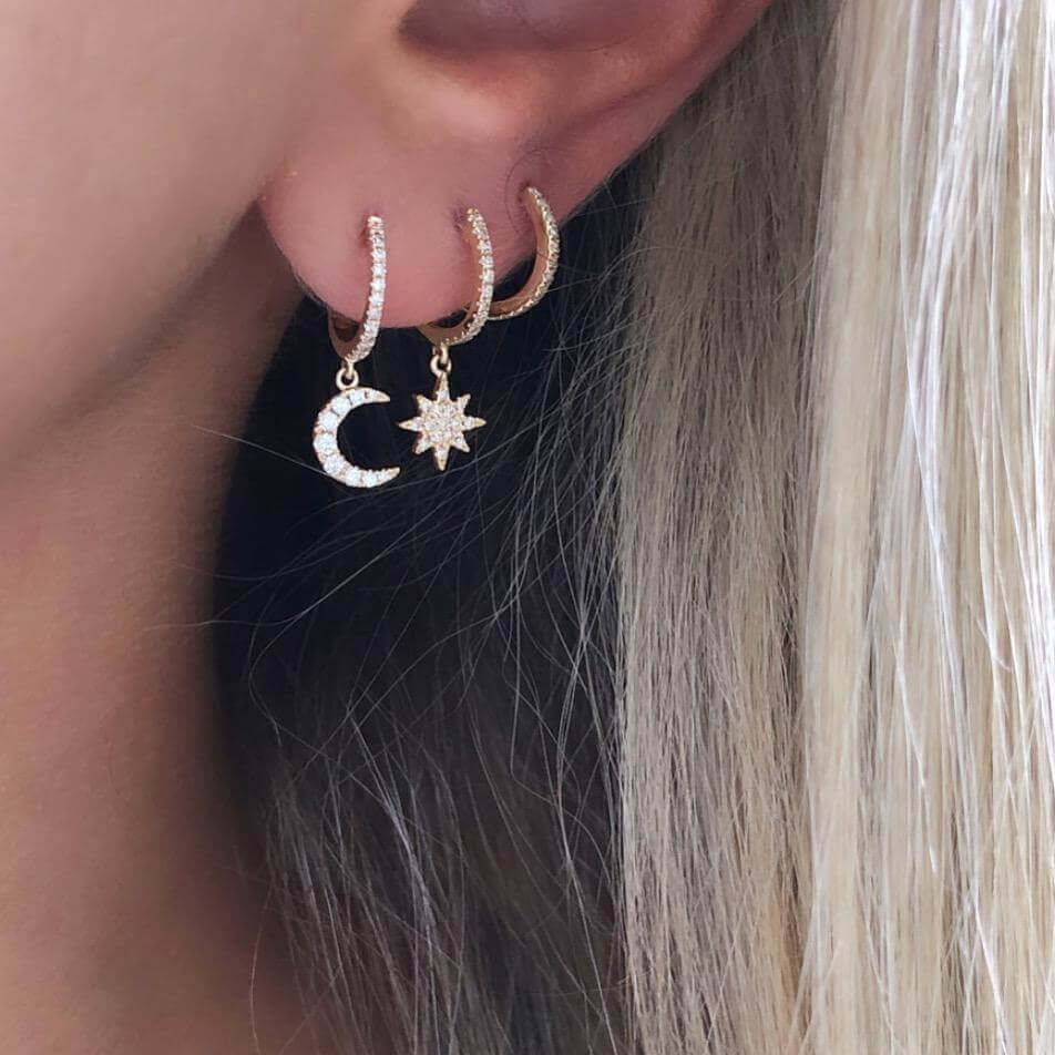 Woman wearing celestial-themed gold earrings with moon and star charms from our jewelry collection.