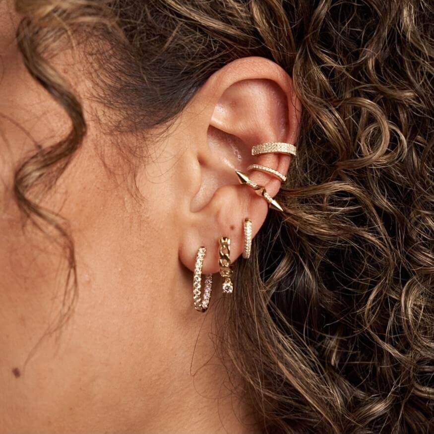 Woman's ear adorned with multiple gold earrings from our luxury jewelry collection.