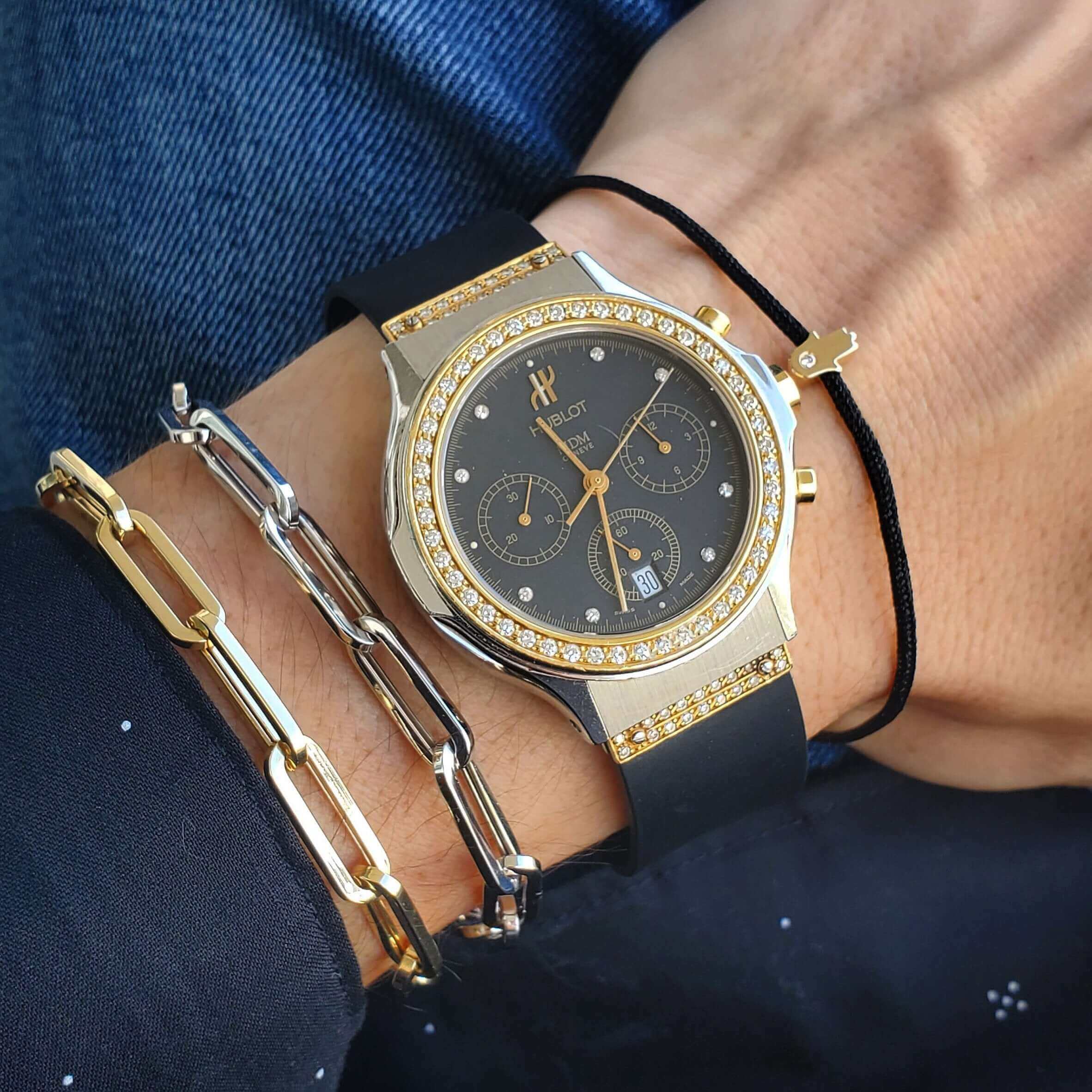 Stylish gold and black wristwatch with diamond accents, paired with elegant metal bracelets for a modern jewelry statement.