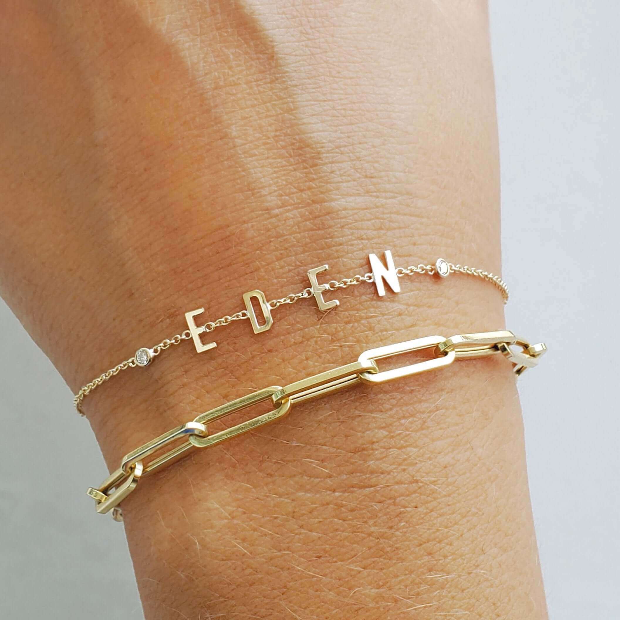 Gold personalized letter bracelet and chain link bracelet on wrist from our jewelry collection.