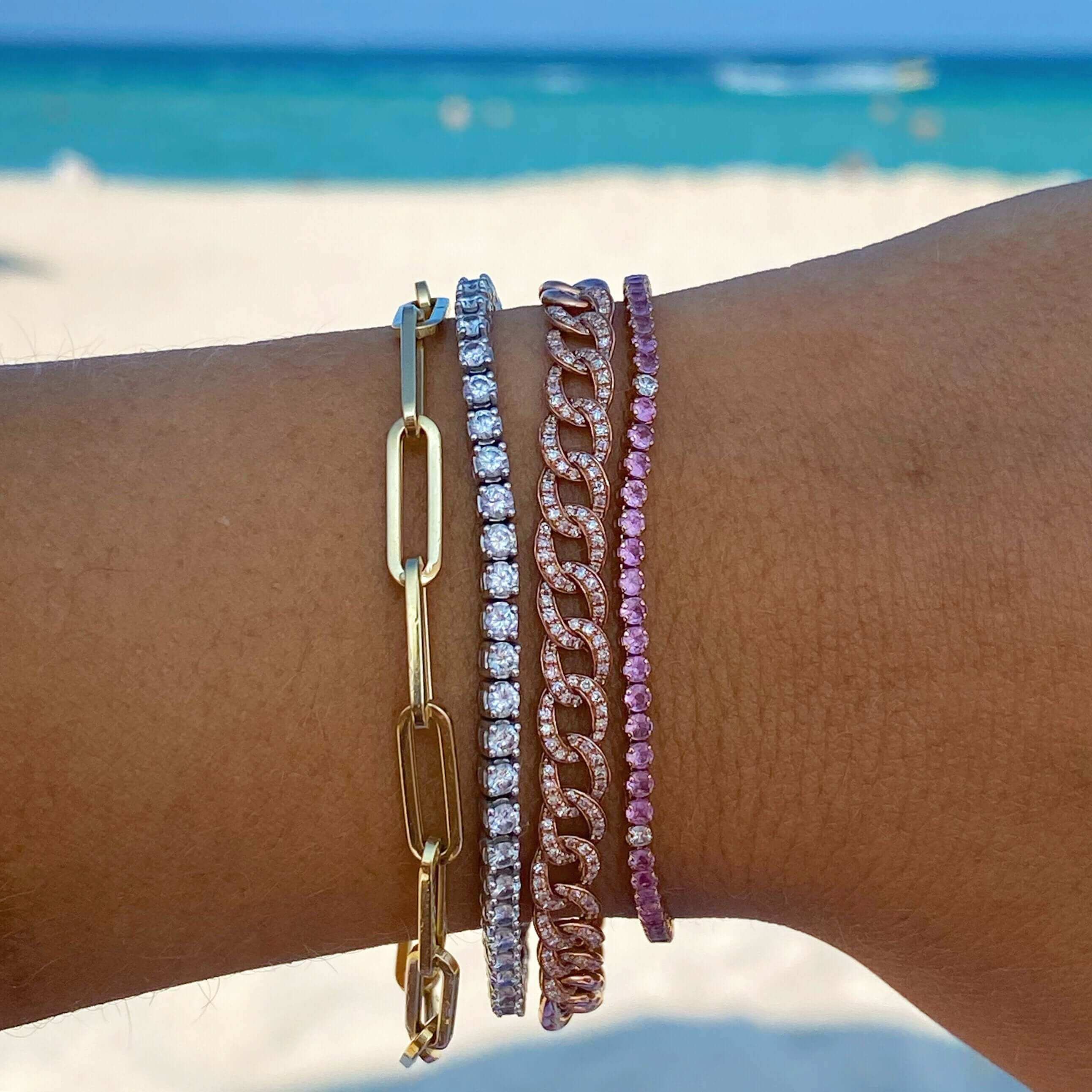 Stylish layered gold, silver, and rose gold bracelets by the beach from our luxury jewelry collection