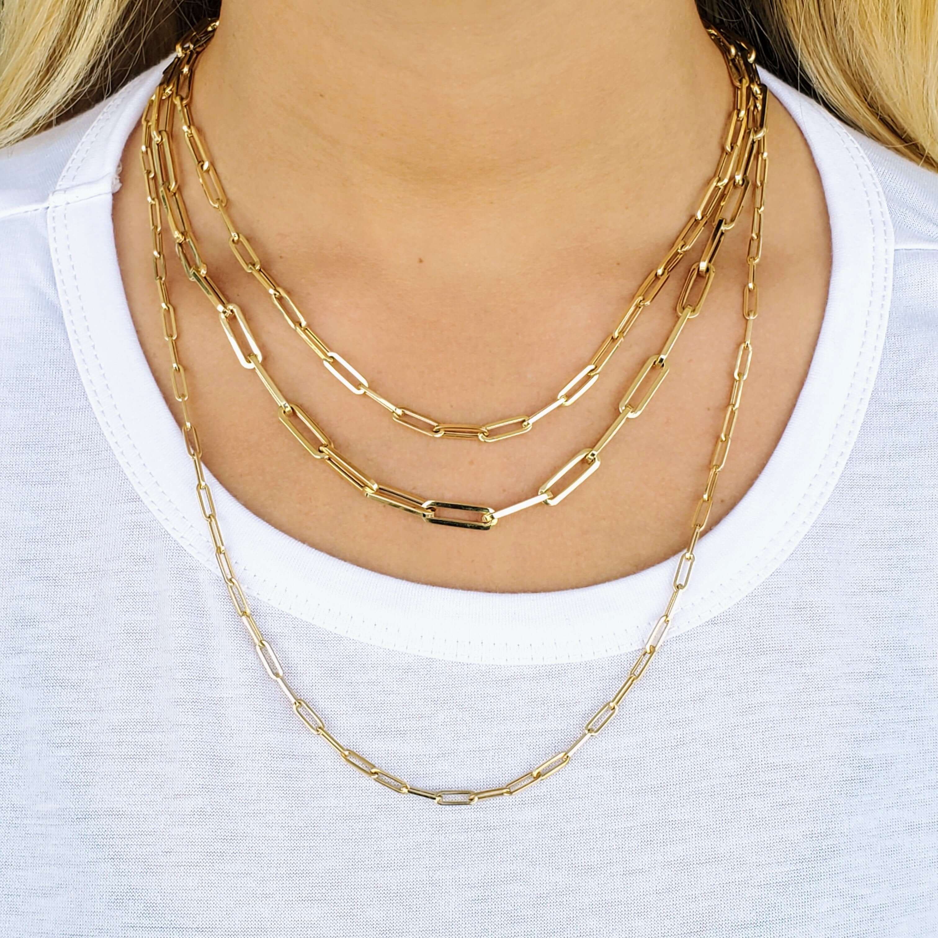 Layered gold chain necklaces on white shirt - elegant jewelry design.